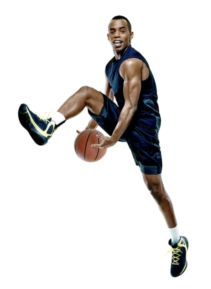 Man in mid-air holding a basketball, wearing a blue sports outfit and sneakers, isolated on white background.