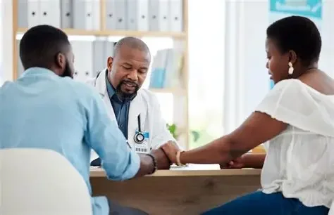 A healthcare professional is comforting a woman in a medical office, holding her hand.