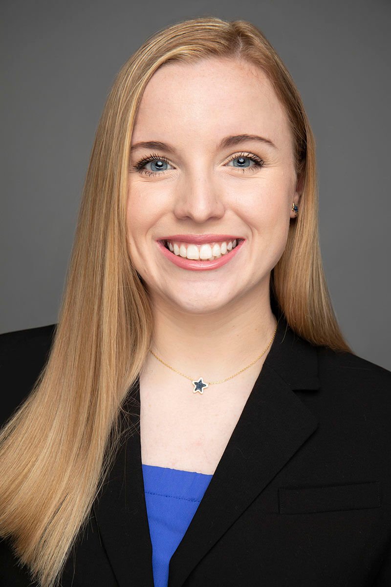 Smiling woman wearing a black blazer and star necklace