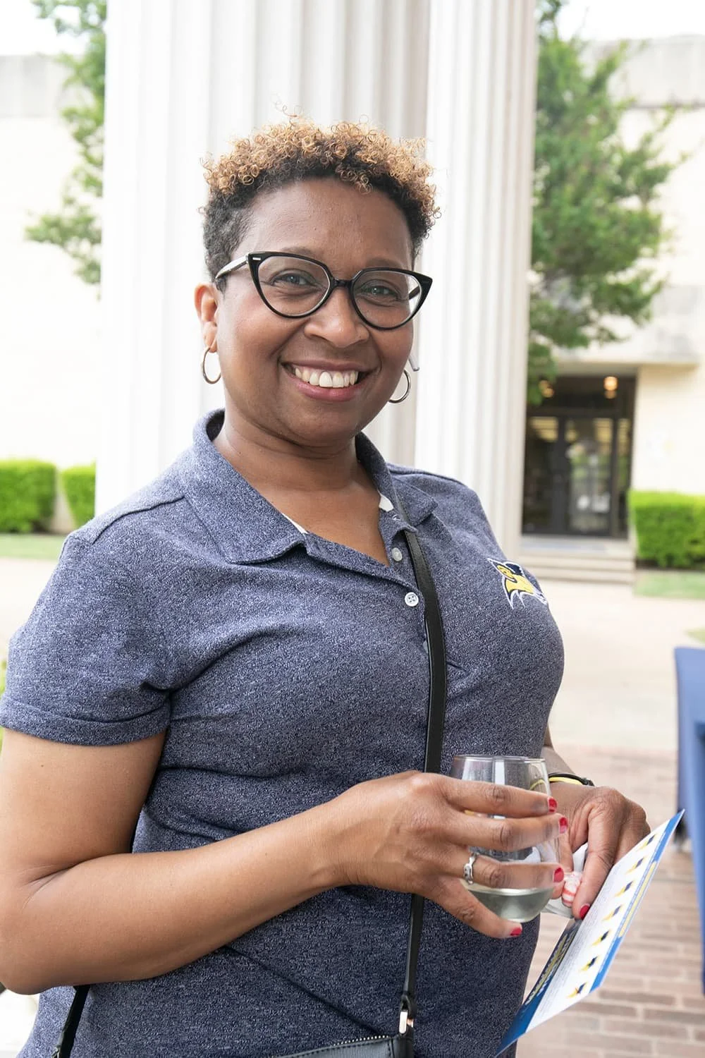 Smiling woman holding a glass and a brochure outdoors