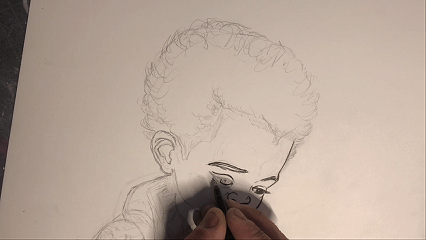 Hand sketching a detailed portrait of a person on paper.