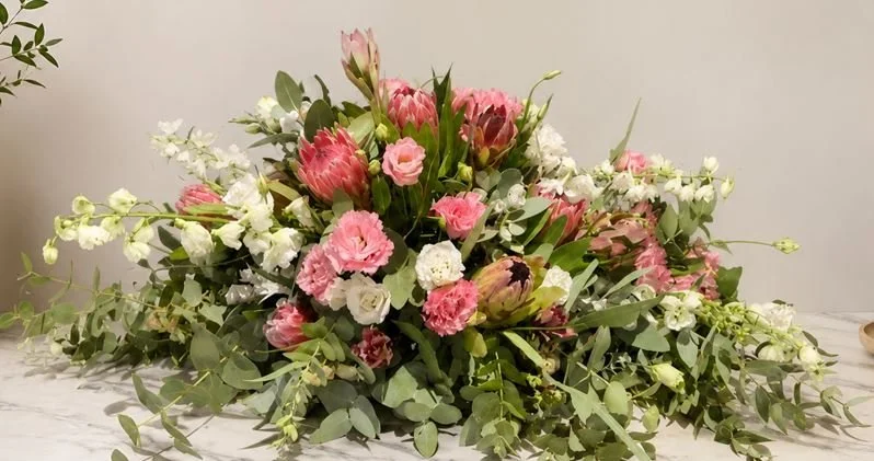 A floral arrangement with pink and white flowers and green foliage on a surface.