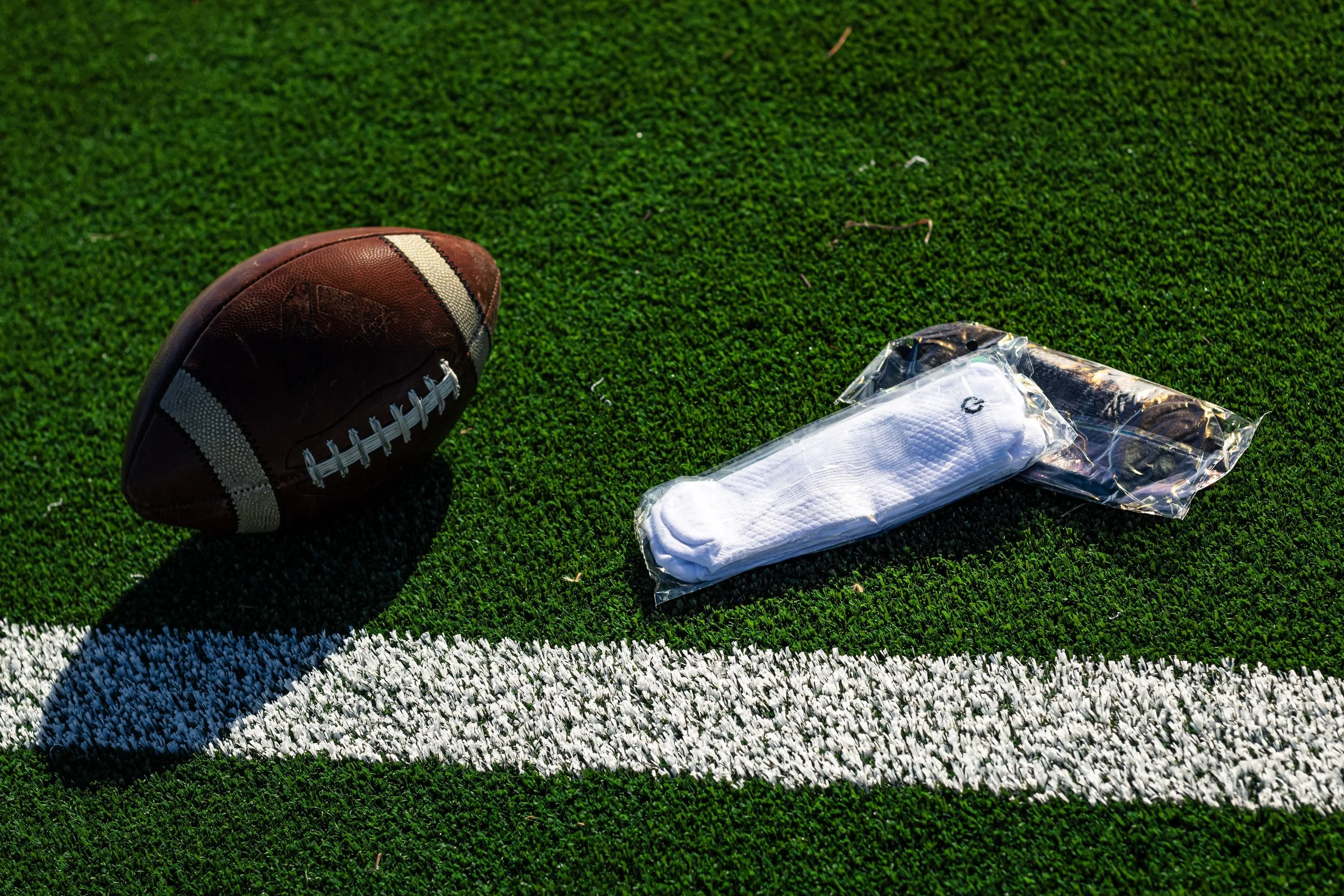 American football and packaged ONE socks on a football field turf, near a white line.