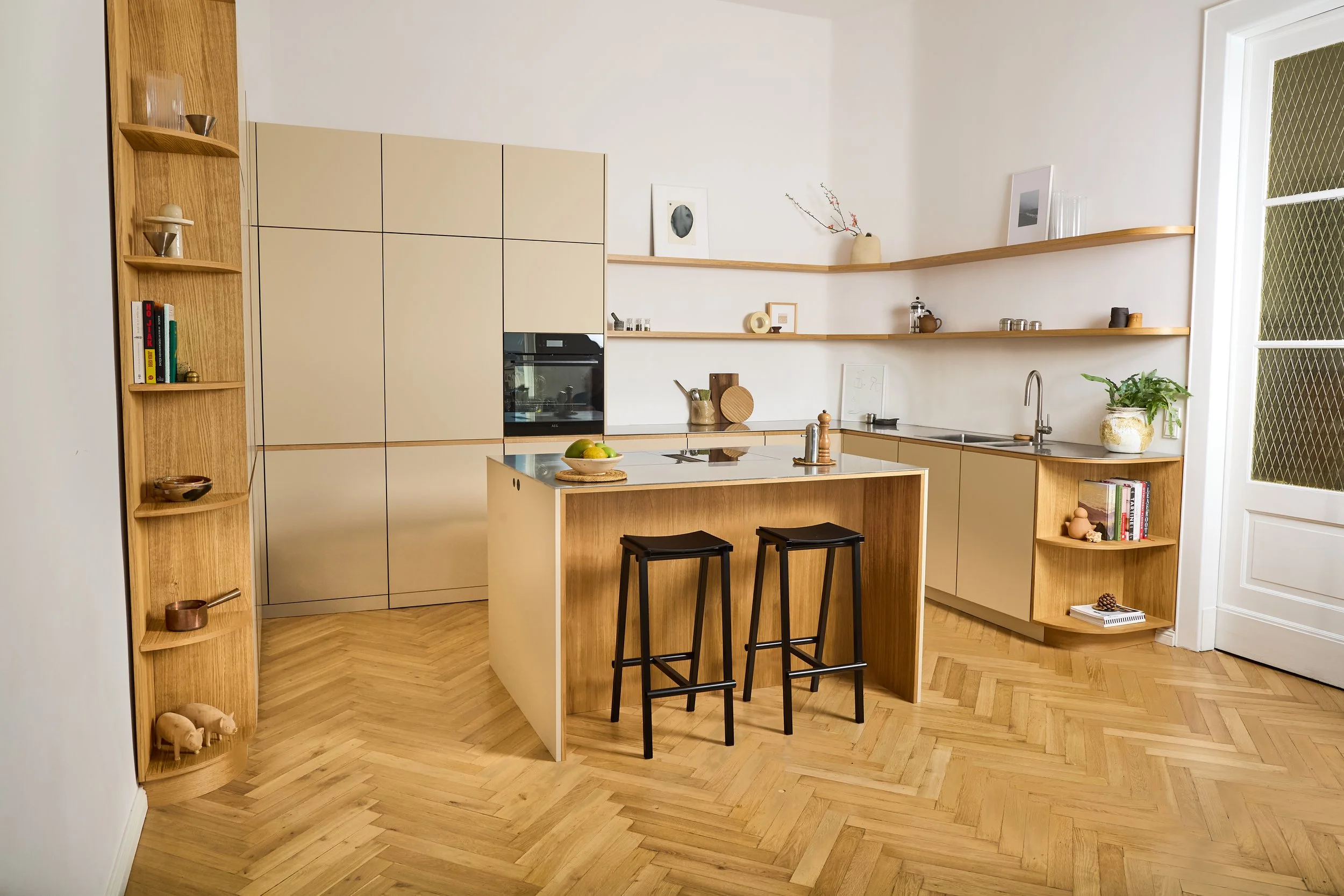 Moderne Küche mit Holz- und Beigefarbenen Schränken, einer Kücheninsel mit Barhockern, offenen Wandregalen, Holzboden und viel natürlichem Licht.
