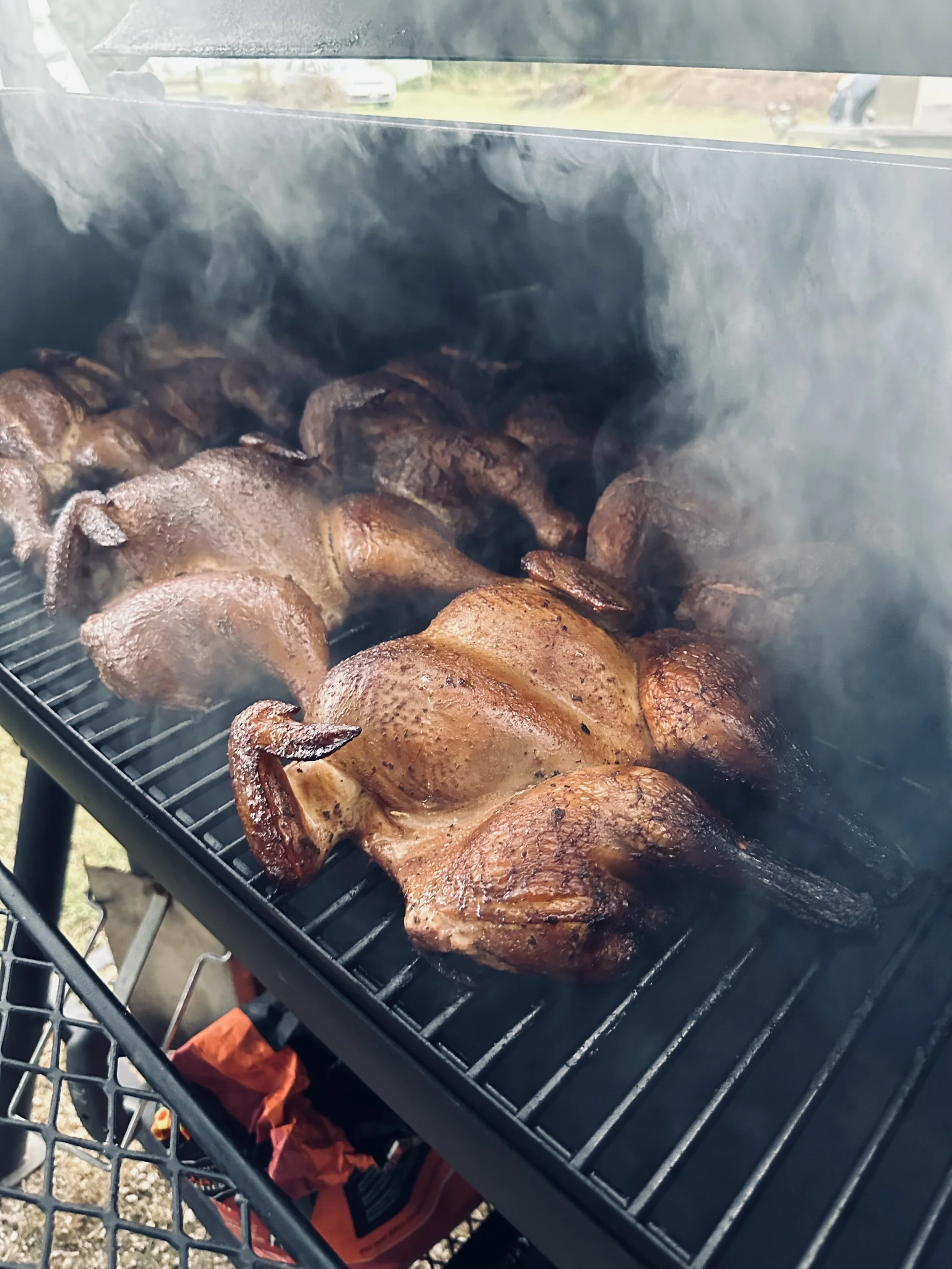 Smoked chicken on a grill with smoke rising.