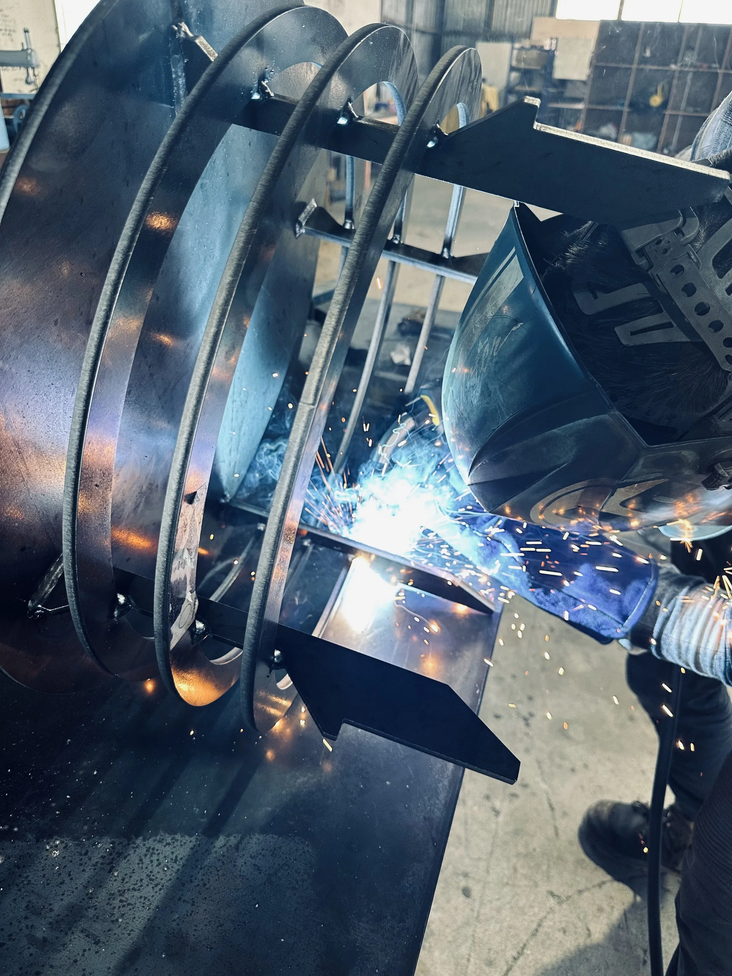 Person welding metal rings in a workshop, sparks flying.