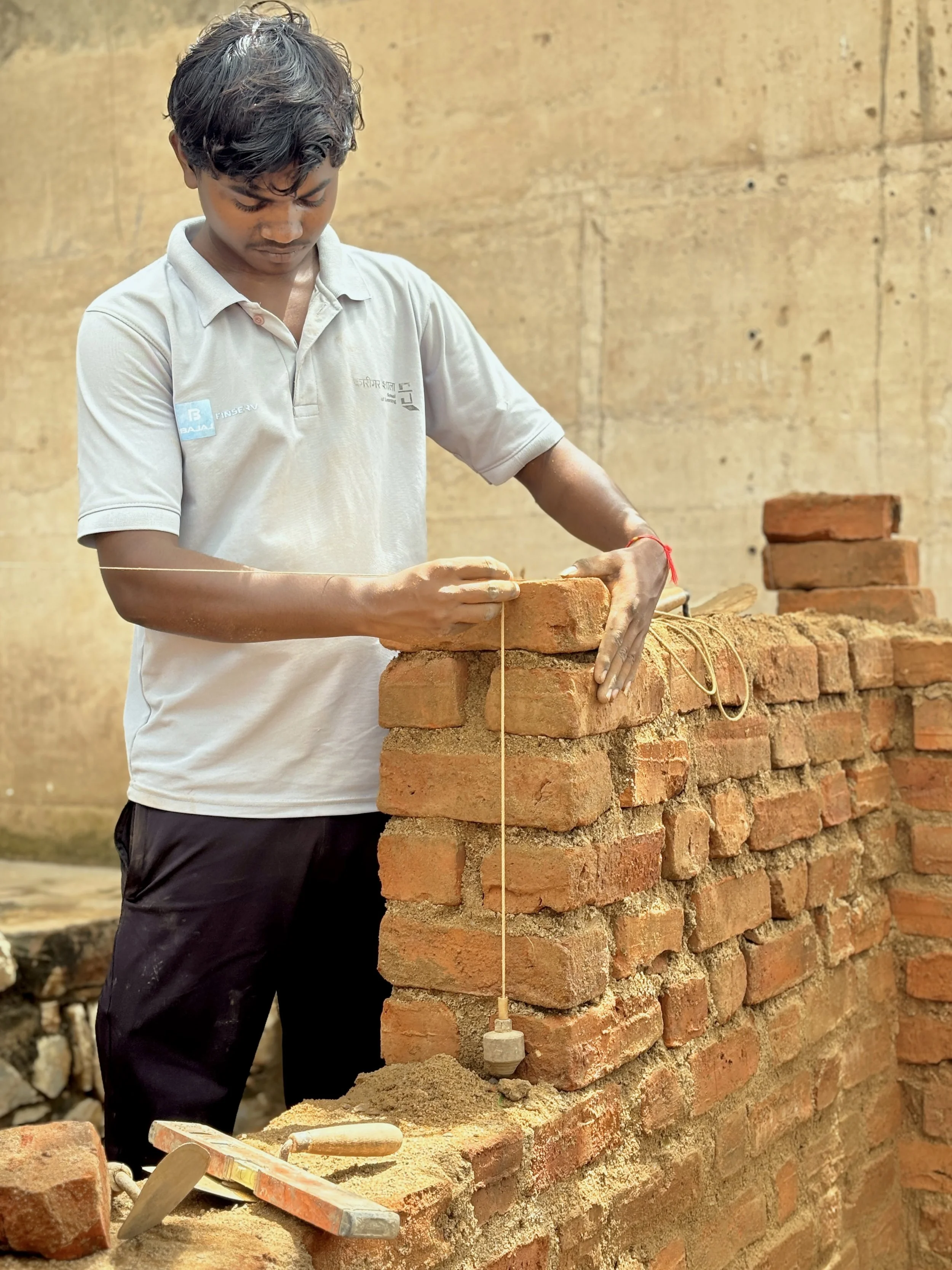 Young man building a brick wall using bricks, mortar, and a string line for leveling