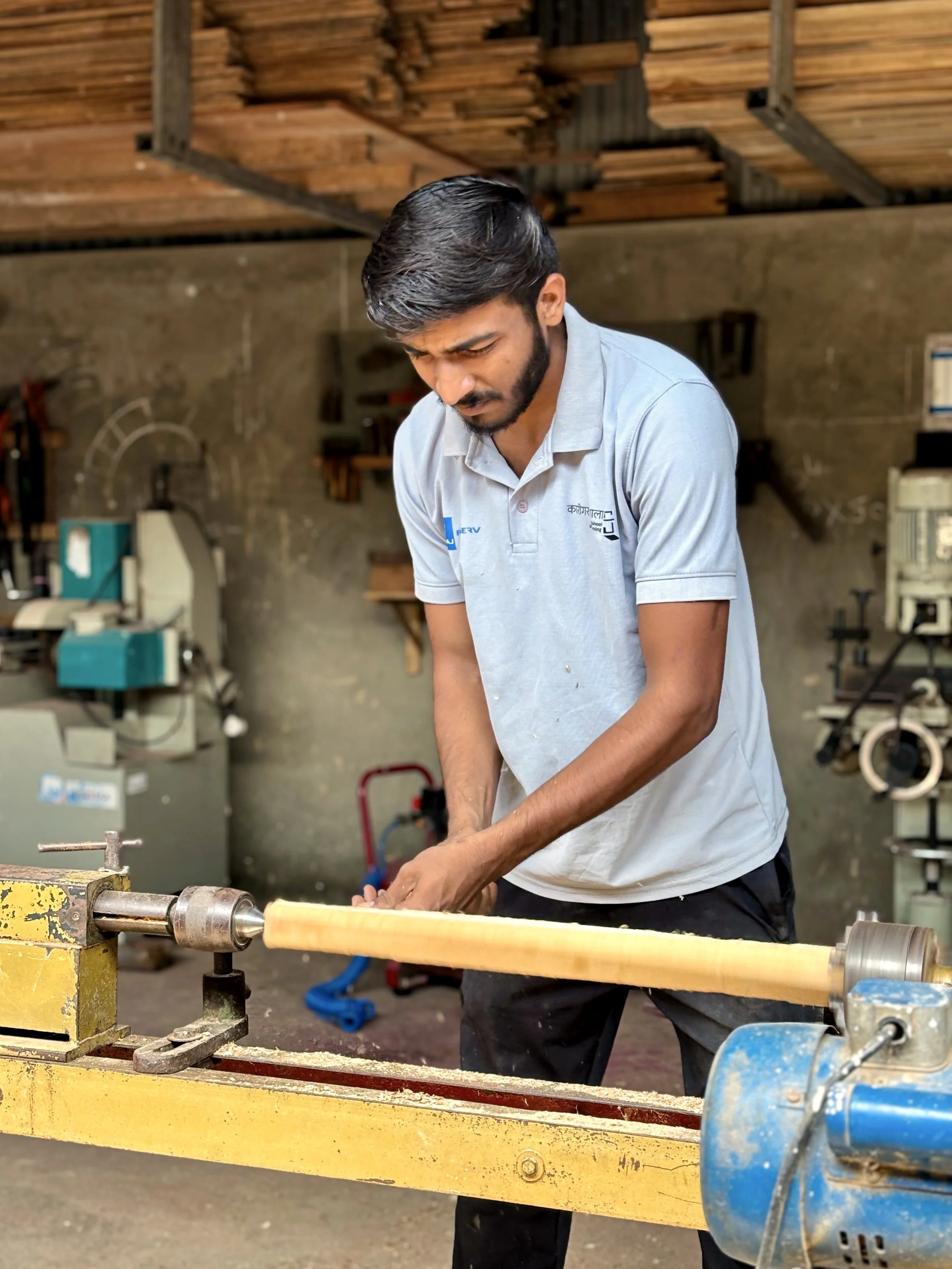A man working on a woodworking lathe in a workshop.