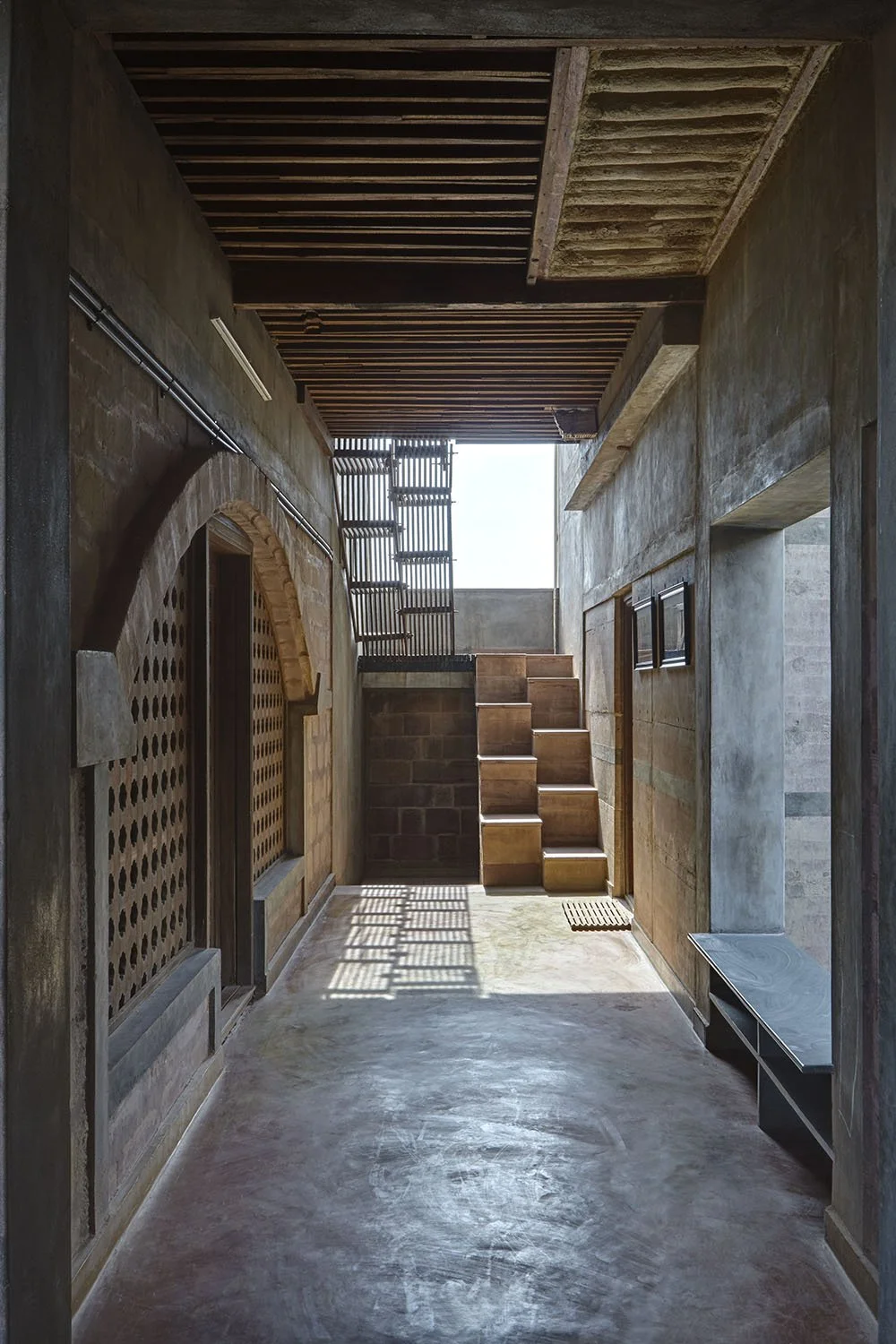 Interior courtyard with concrete flooring, staircase, brick walls, and wooden ceiling.