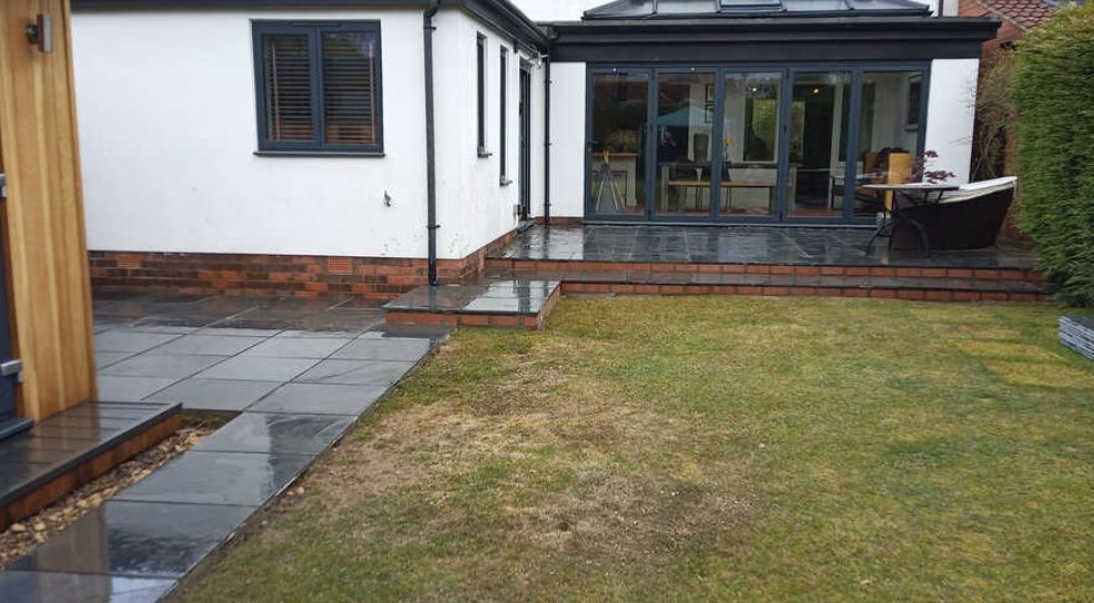 Backyard with stepping stones, a lawn, and an enclosed porch with glass sliding doors.