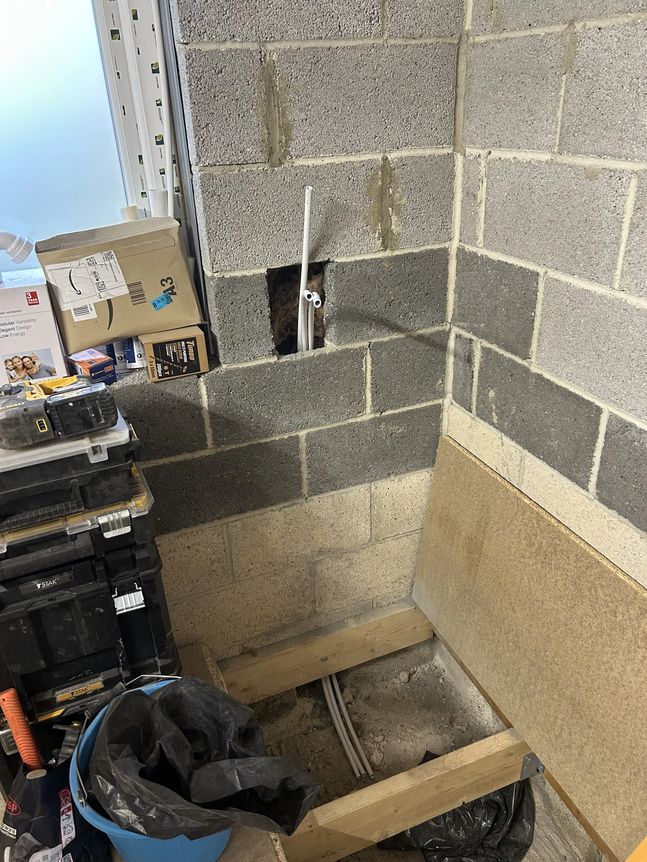 Construction site with unfinished wall, electrical wiring, and tools.