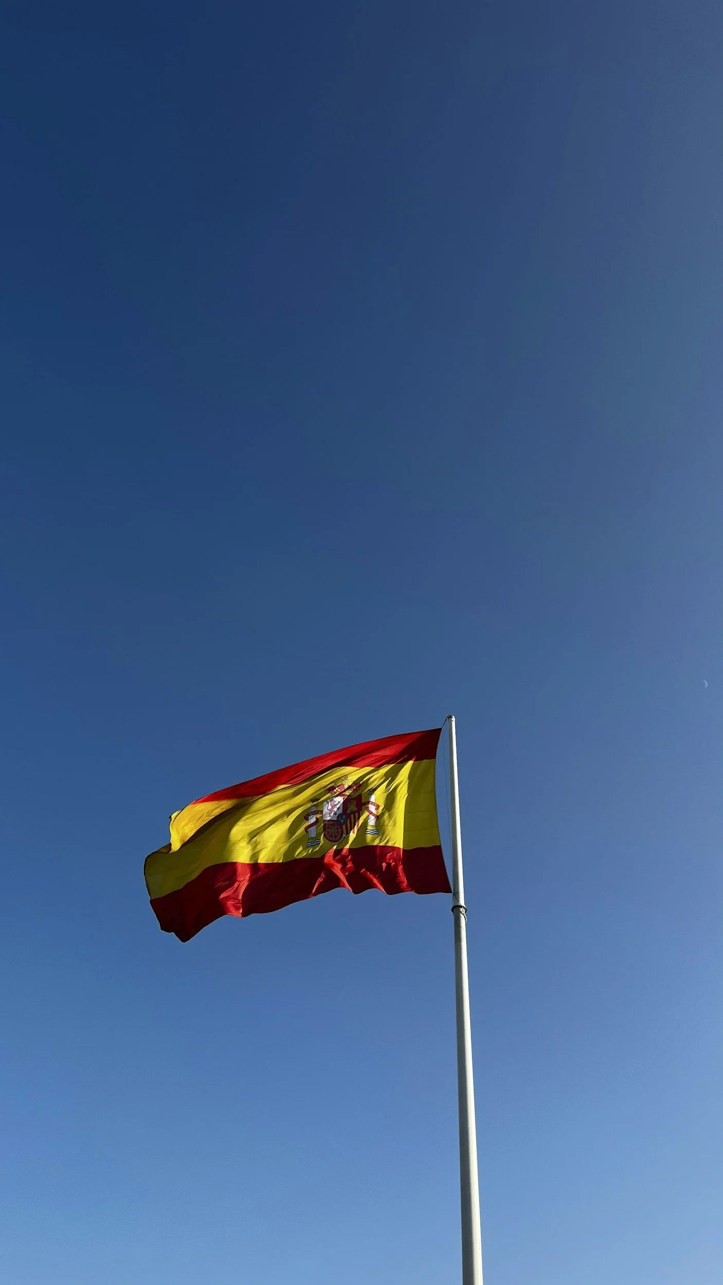 Spanish flag flying against a clear blue sky.