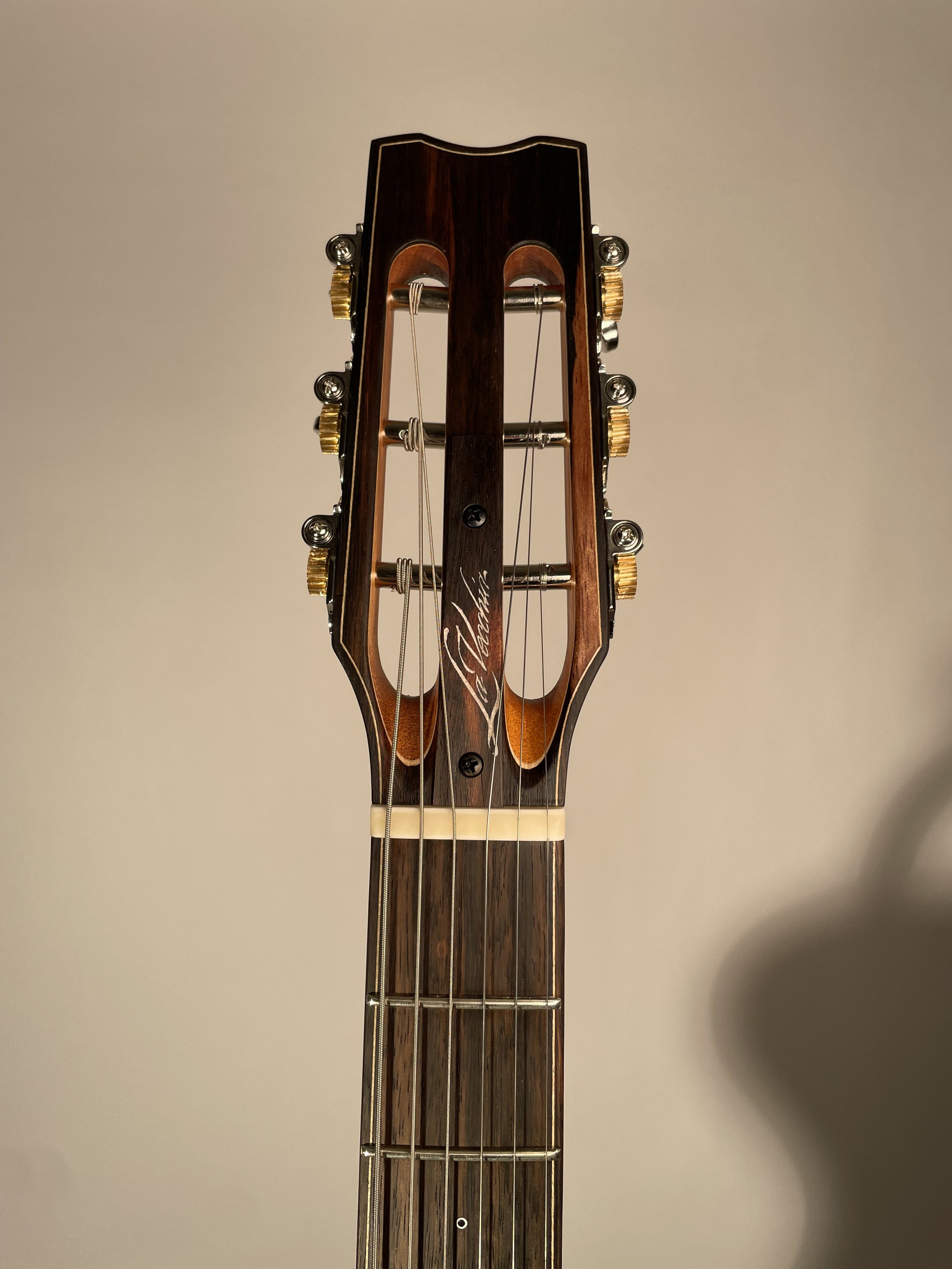 Close-up of a classical guitar headstock with tuning pegs and strings visible.