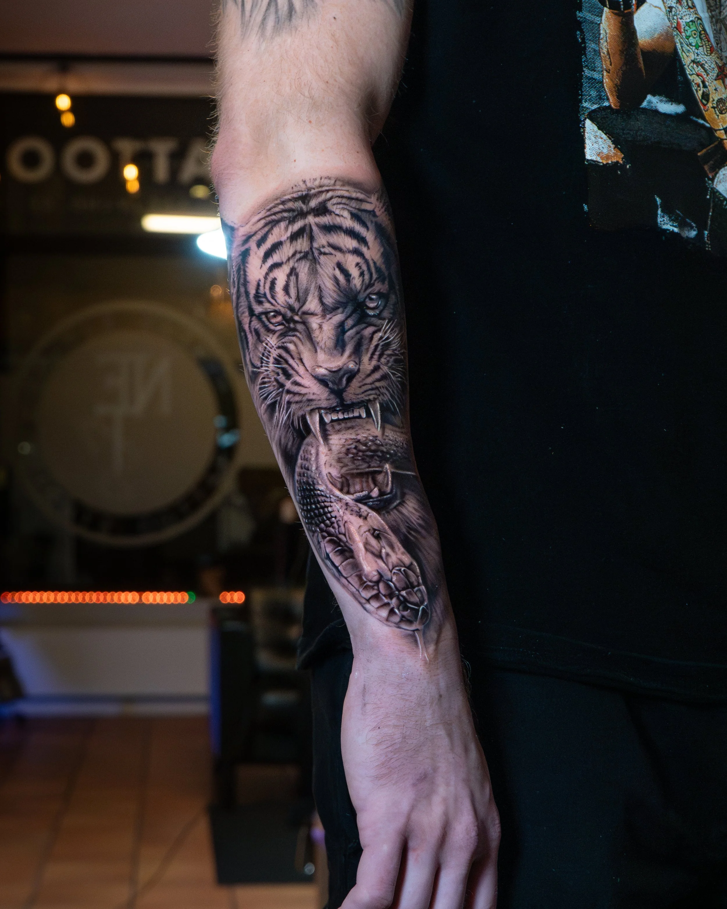 Tatuering av en lejonhuvud och en krokodil på en persons underarm.