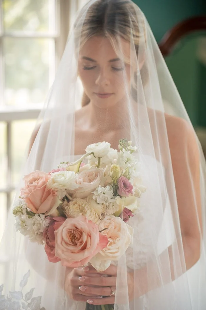 Bride wearing her veil and holding a blush floral bouquet at a Northern Virginia wedding.`