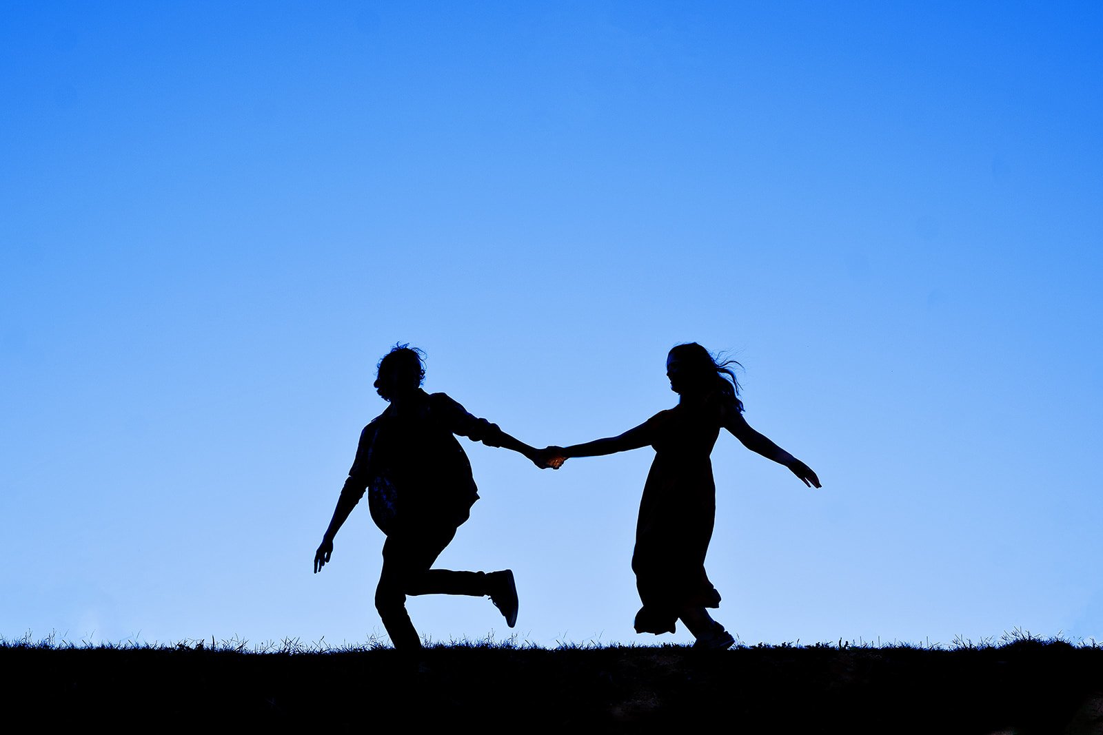 Aly and Chris holding hands in silhouette against the evening sky in Richmond