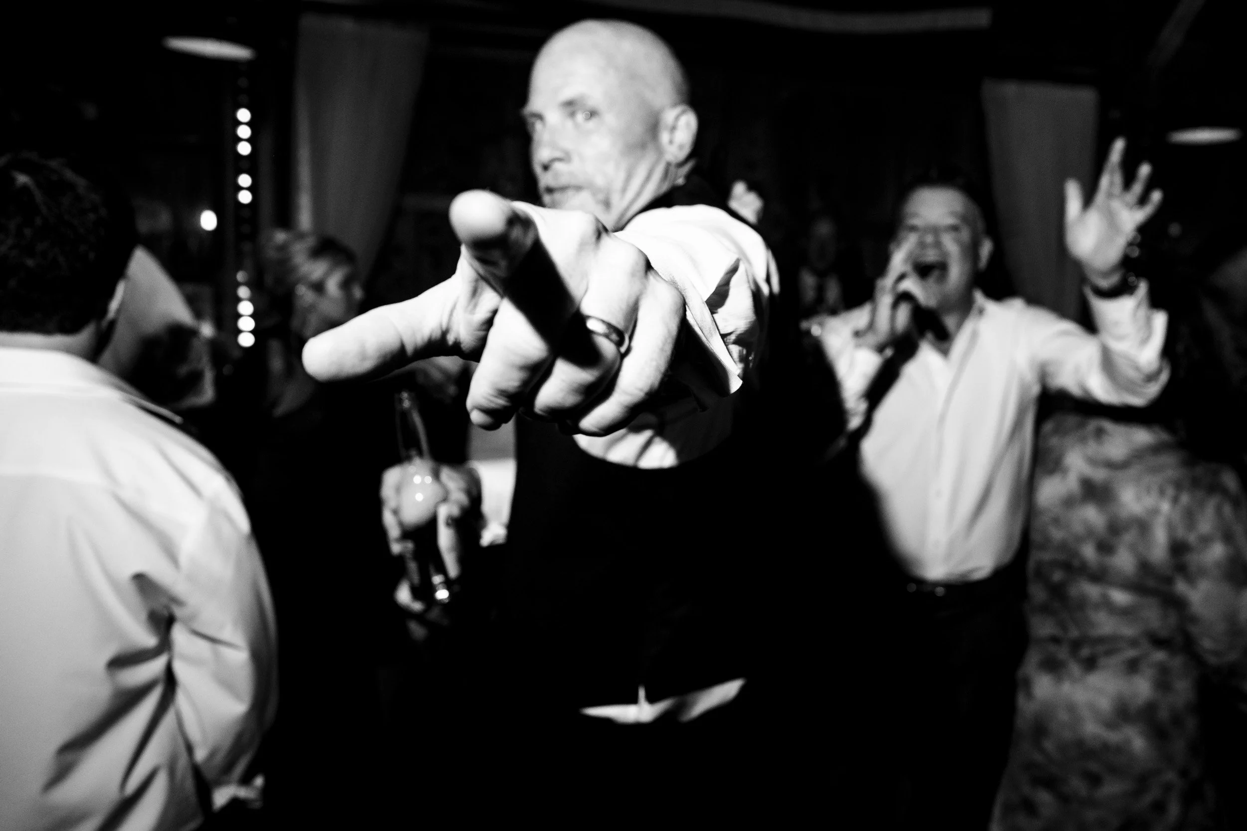 A guest points toward the camera in a black-and-white dance-floor photograph.