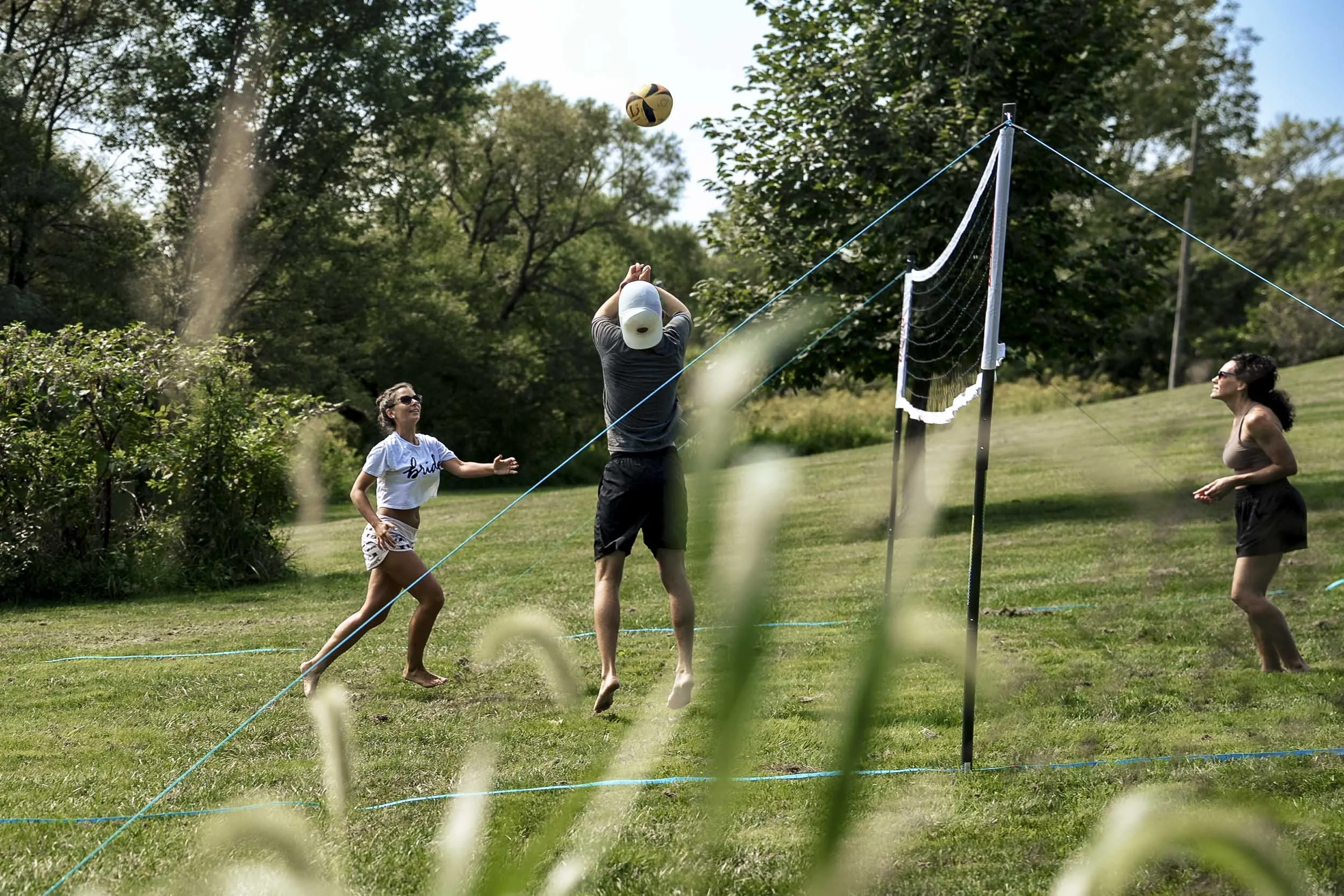 Sarah and Andrew playing volleyball against Sarah’s friend on a grassy court before their Northern Virginia wedding.