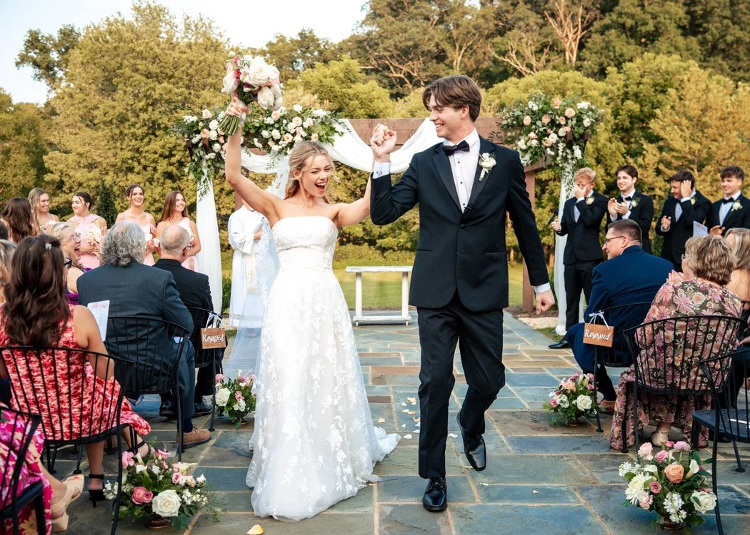 Fiona and Cole celebrating as they walk back down the aisle as newlyweds.`