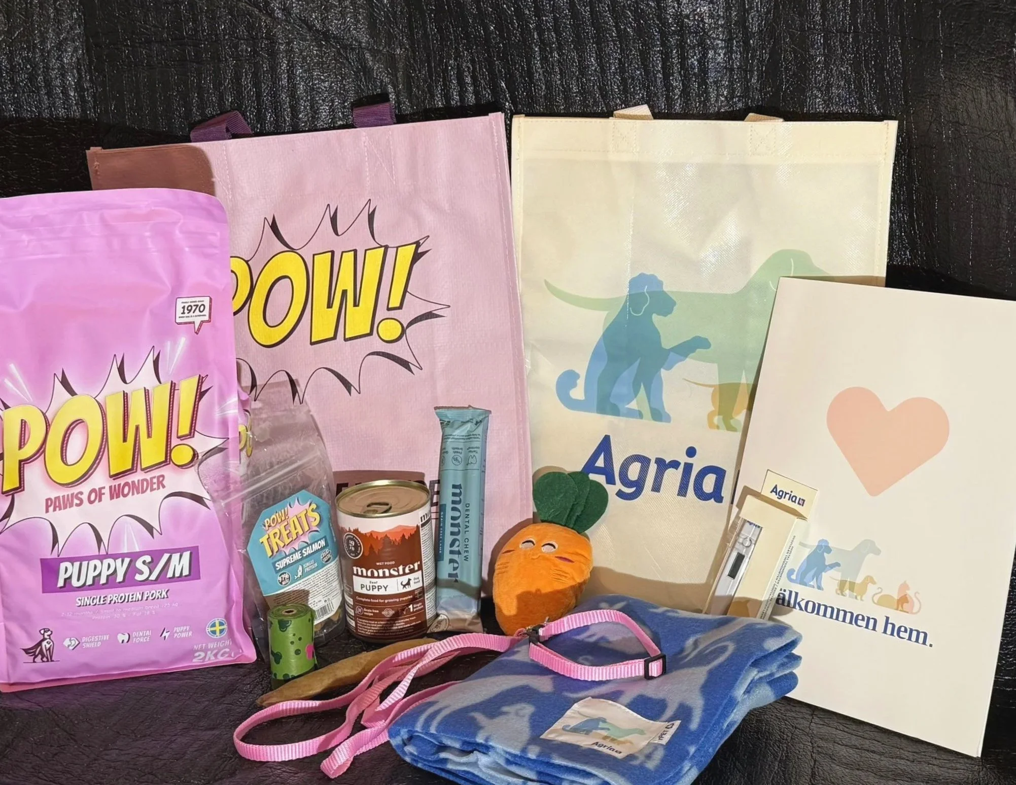 Så här kan ett gratis paket vid köp av valp se ut: Hundmat, kattmat, leksaker, förpackningar, ett orange filt, ett blått halsband, och olika soppåsar med djurmotiv.