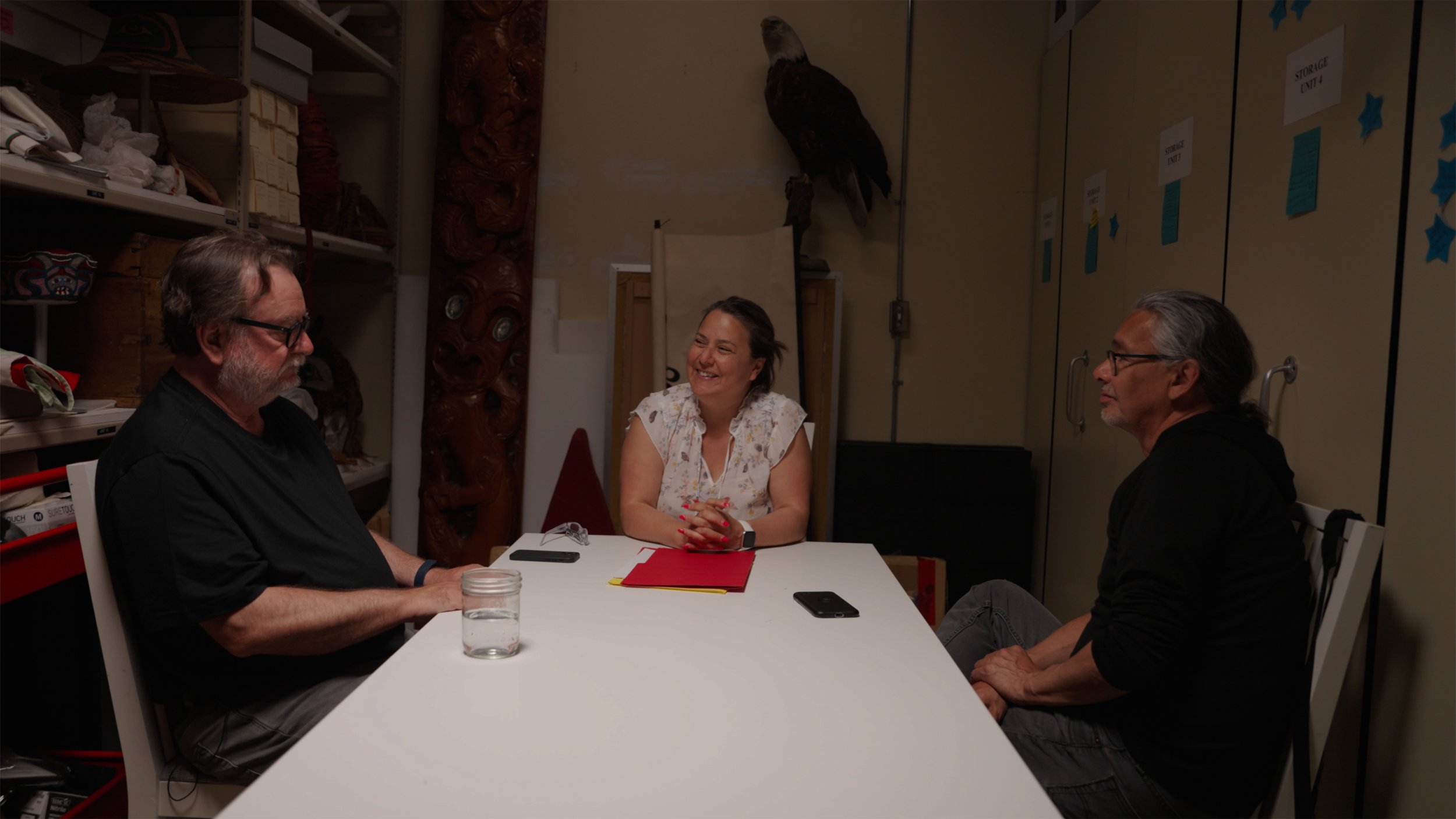 Juanita Johnston strategizing with art dealer Donald Ellis and director Neil Diamond about bringing home a mask that was confiscated in 1921 during the Potlatch Ban.