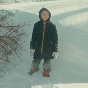 a color image from circa 1965 of a little girl all bundled up and standing in snow