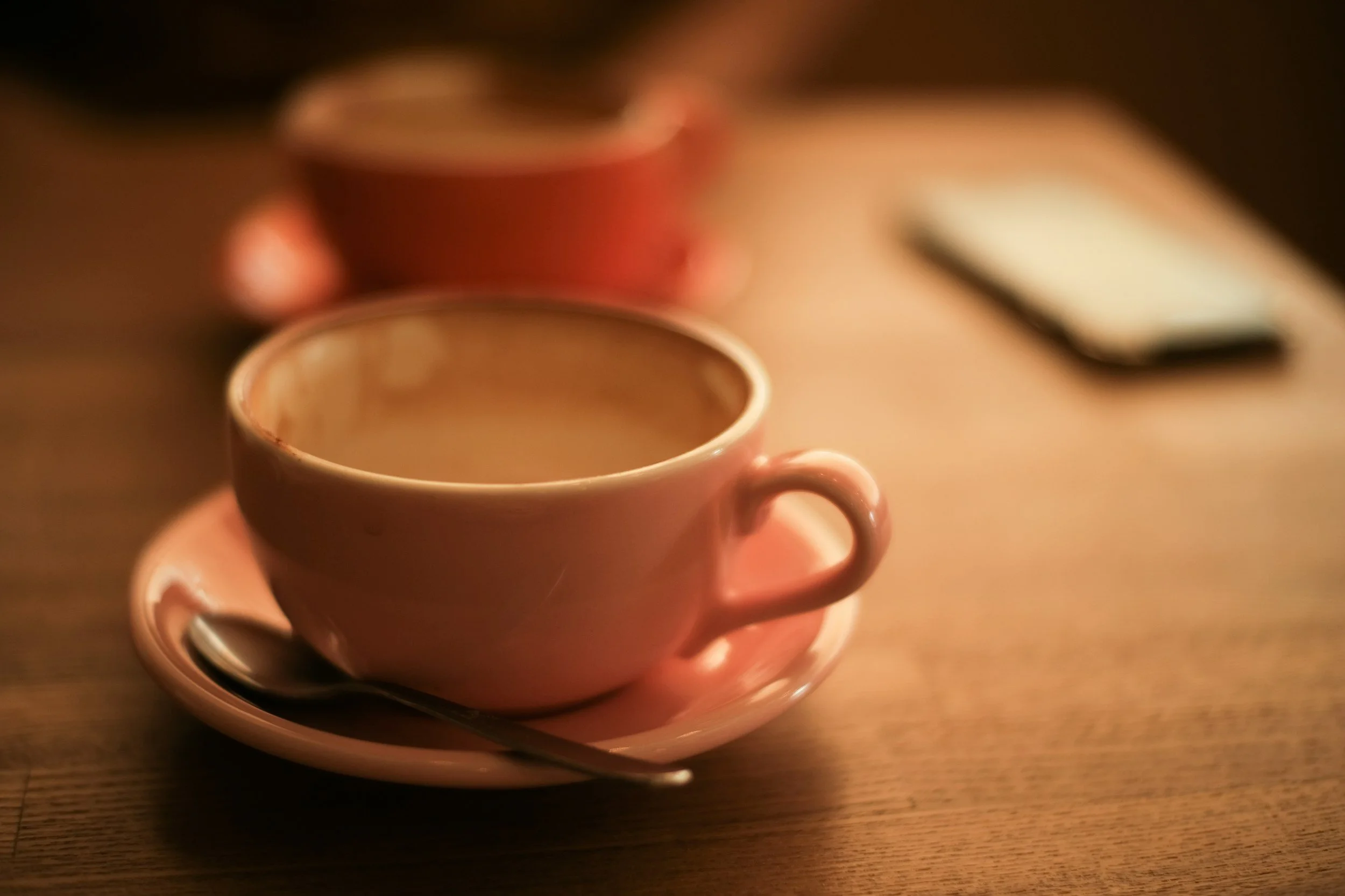 A ceramic coffee cup on a warm wooden surface in soft natural light, evoking the human quality of word of mouth referrals when searching for a therapist.