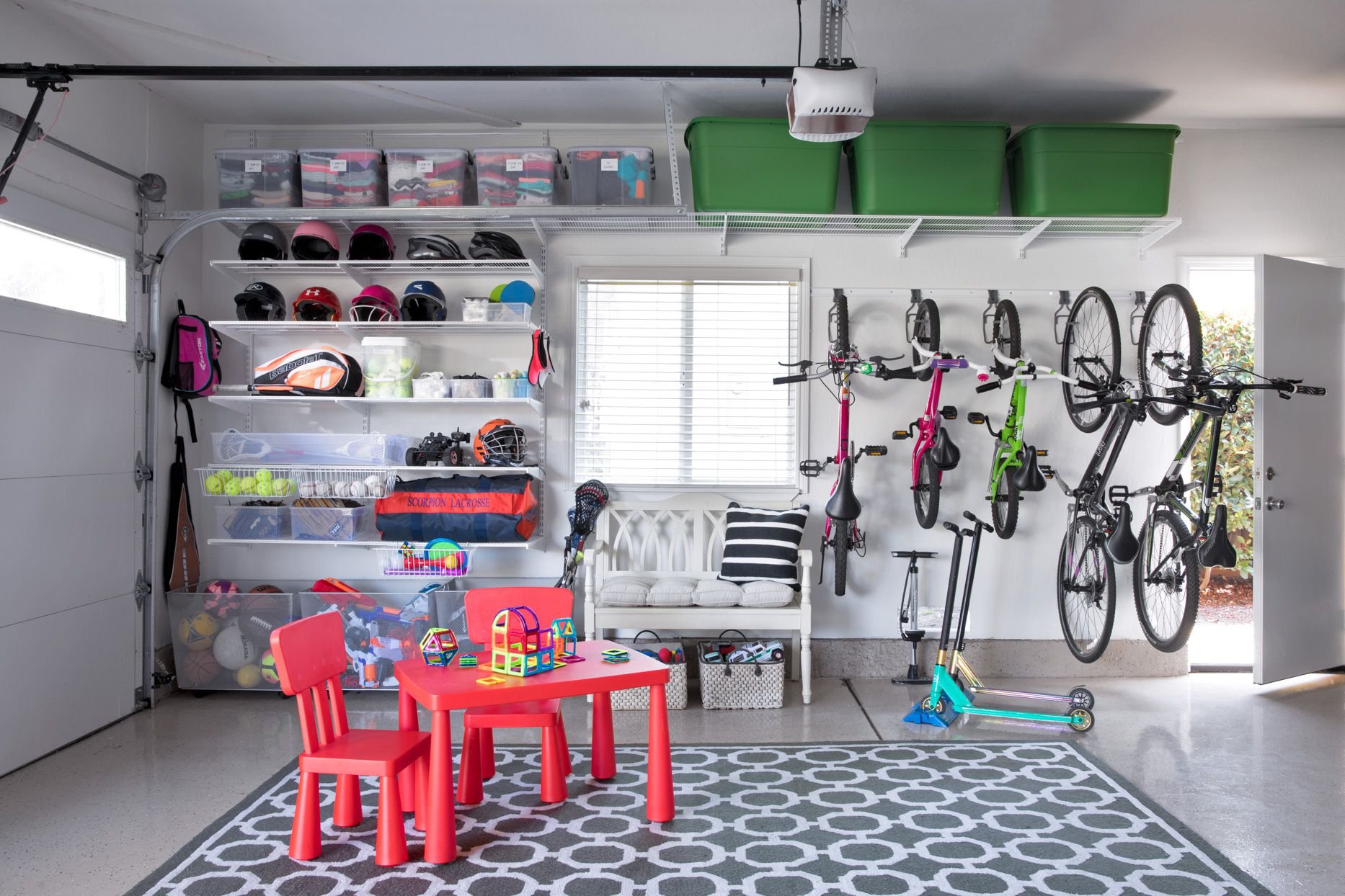 Organized family garage featuring wall mounted bike storage, open shelving, and labeled bins for everyday use