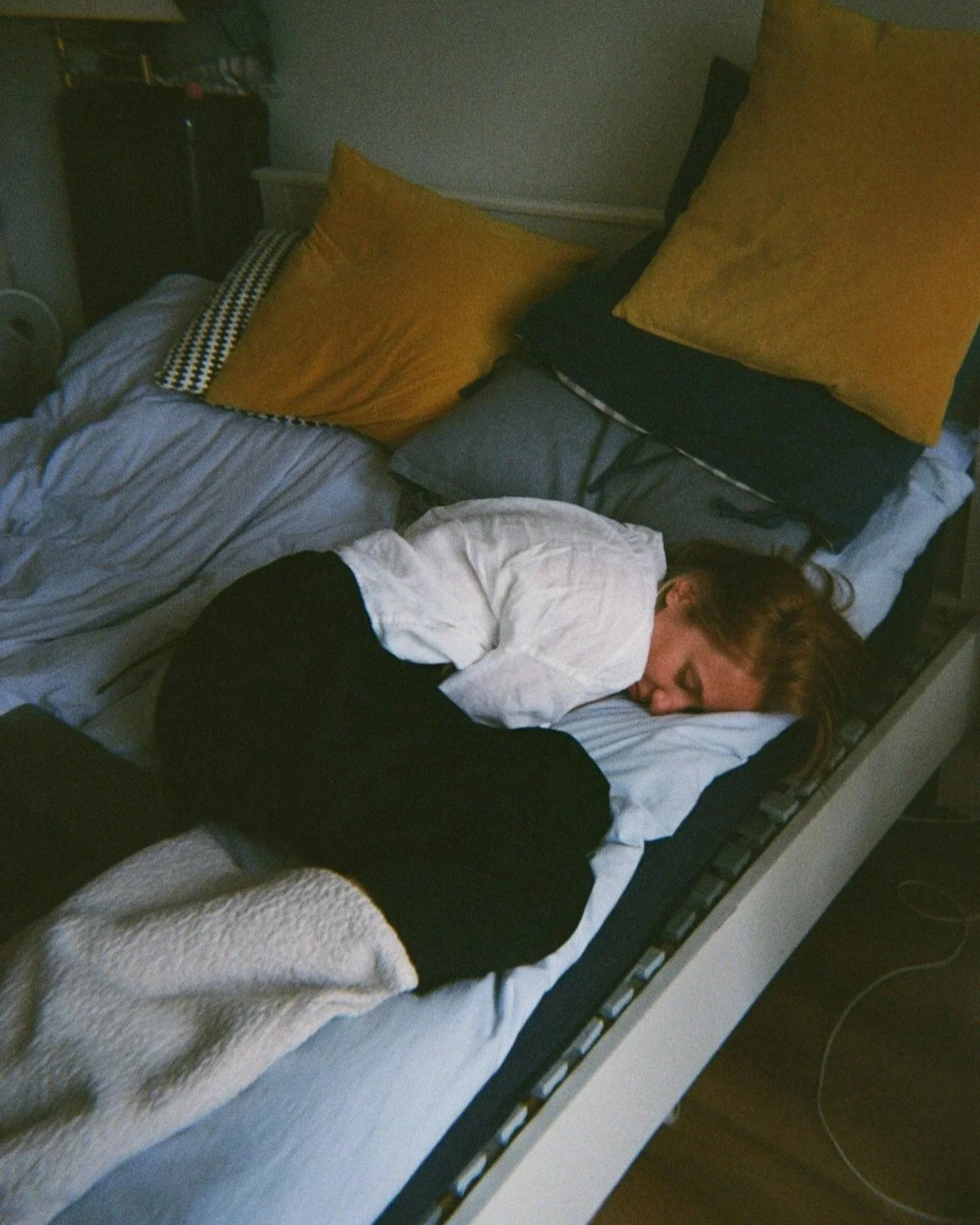 White woman obviously ill and curled up in bed sleeping