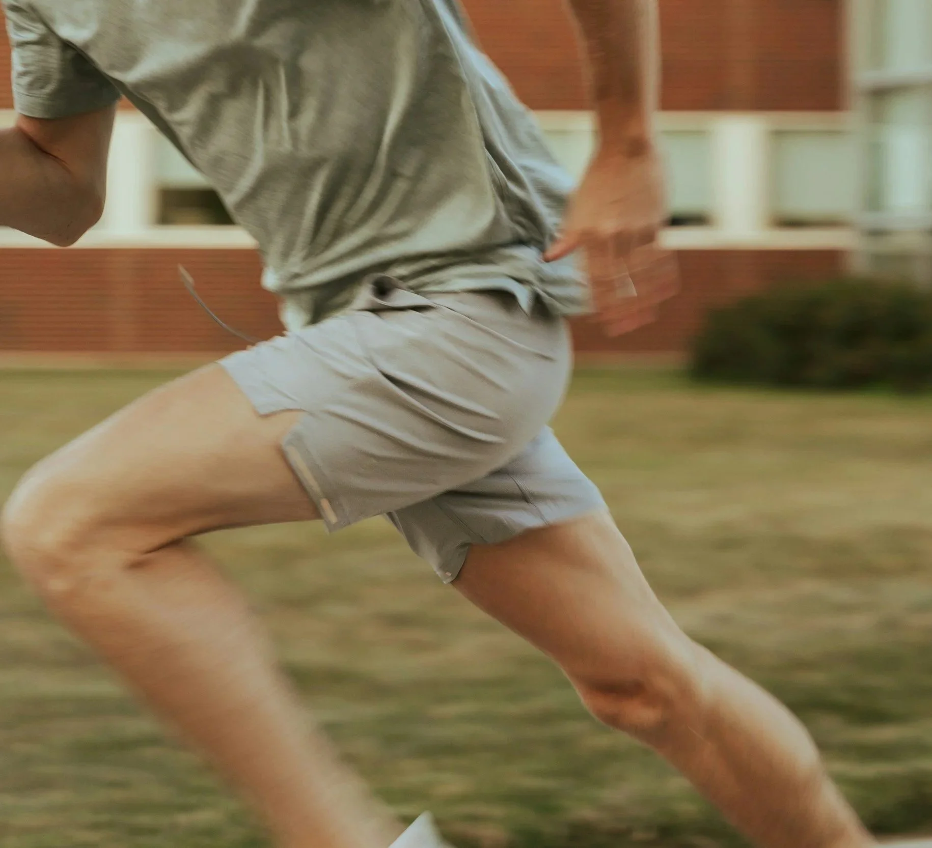 White man in running position wearing green shirt and gray shorts
