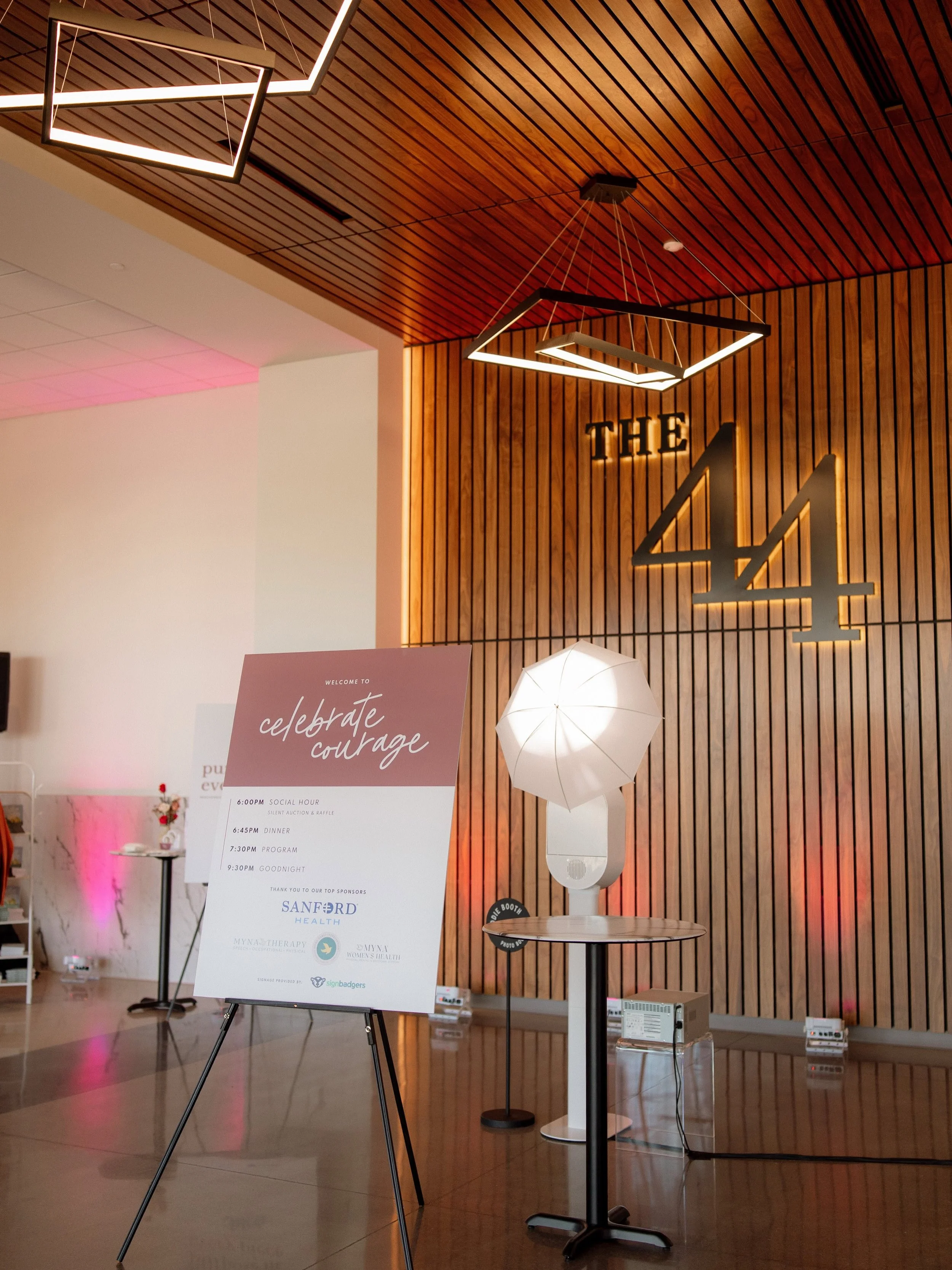 Event space with wooden wall, large illuminated numbers '41', a sign with event details, and various lighting fixtures, including a white umbrella light and modern ceiling lights.