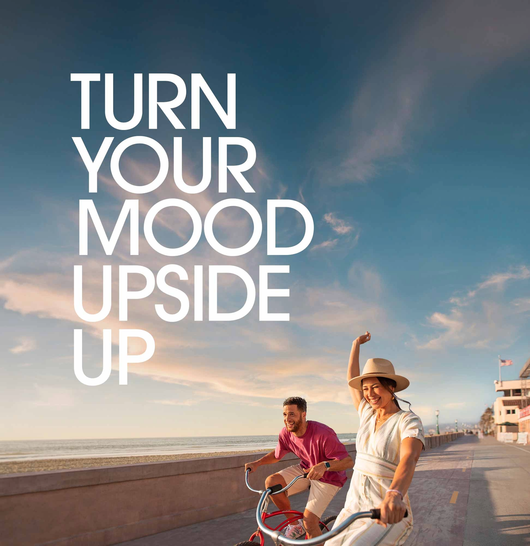 Woman and man riding beach cruisers on the boardwalk in mission beach during sunset.