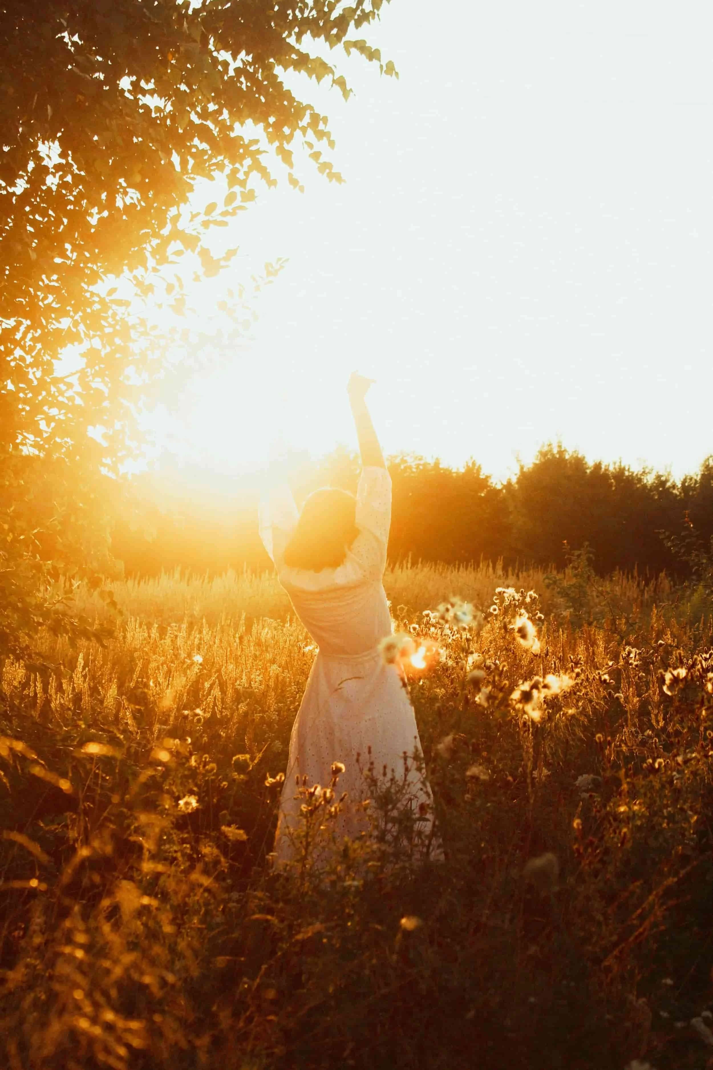 Young woman standing in a sunlit field with arms raised, symbolizing emotional freedom, identity growth, and faith-based counseling support for young adults in Texas.