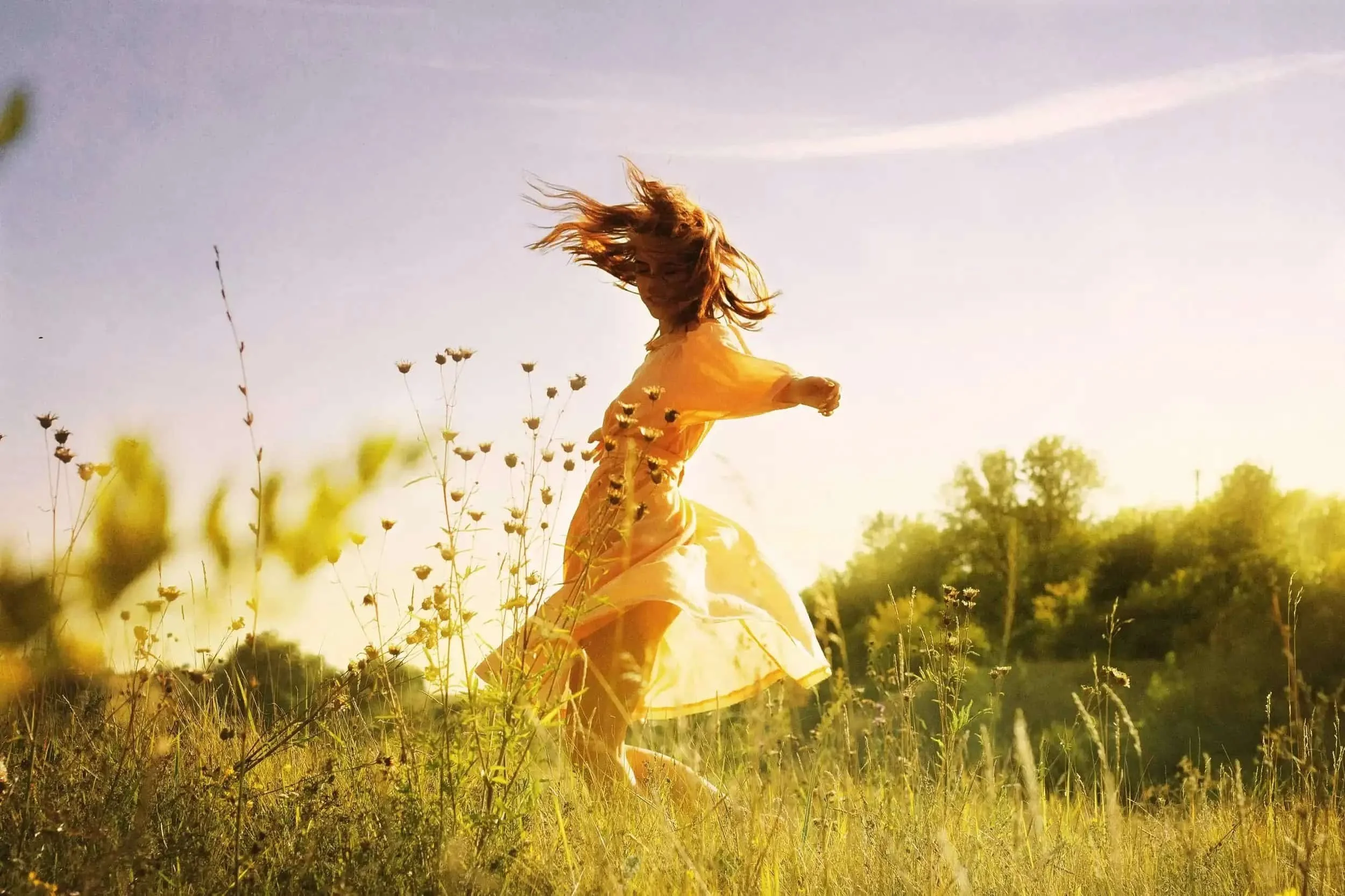 Woman moving freely in a sunlit field symbolizing emotional freedom and healing through Christian therapy in Texas