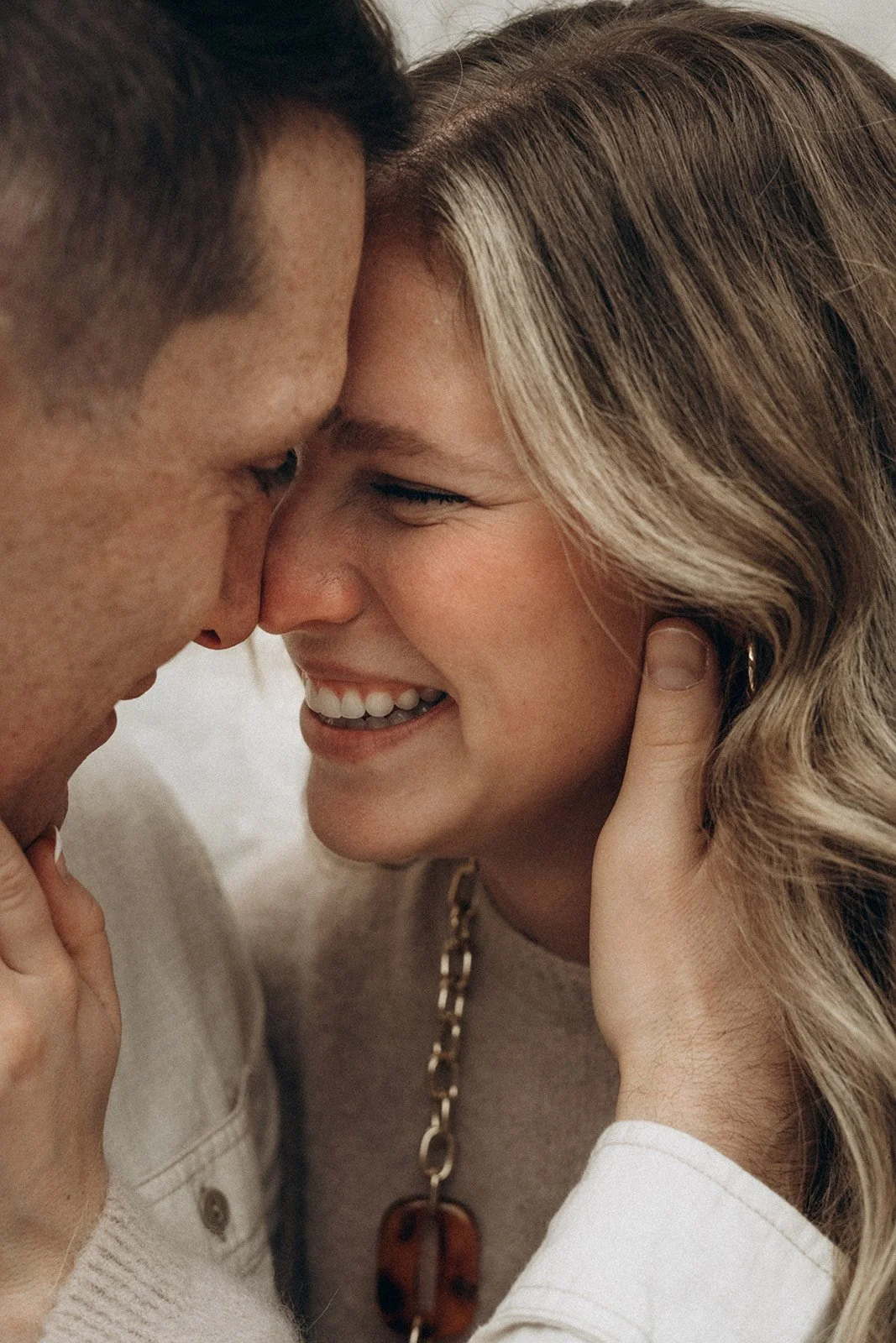 A close-up of a couple touching foreheads, smiling, with eyes closed, showing intimacy and happiness.