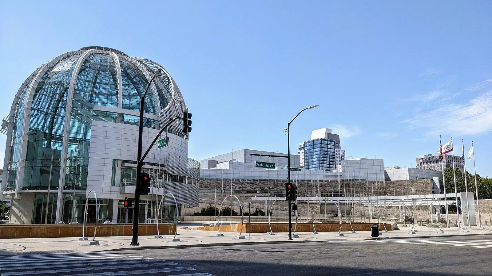 The glass rotunda and white tower of San José City Hall rise above the civic plaza on a sunny day.