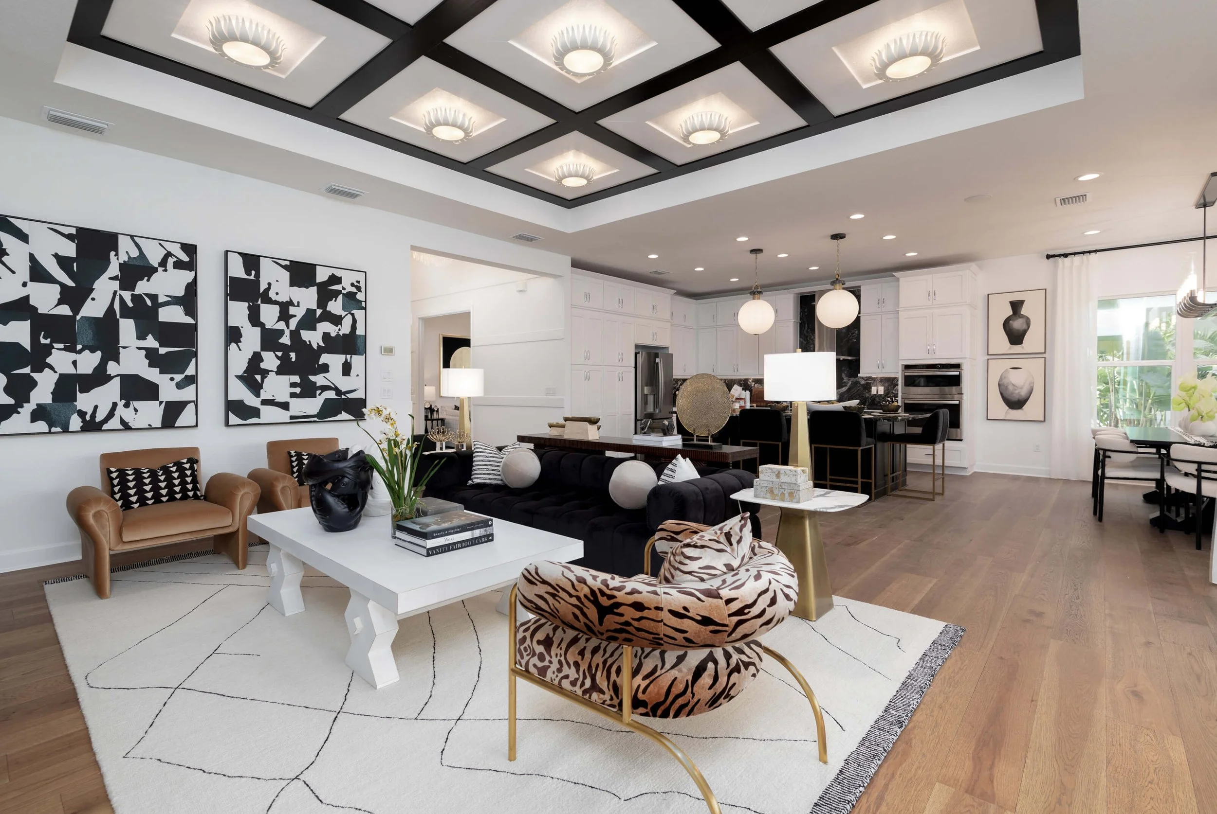 Stylish open-concept living room and kitchen with black, white, and animal print accents, modern furniture, and geometric wall art.