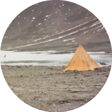 A desert landscape with a pyramid-shaped tent and stars in the night sky.