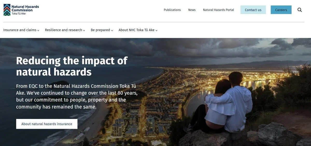A couple sitting on a hill overlooking a city with text information about reducing the impact of natural hazards.