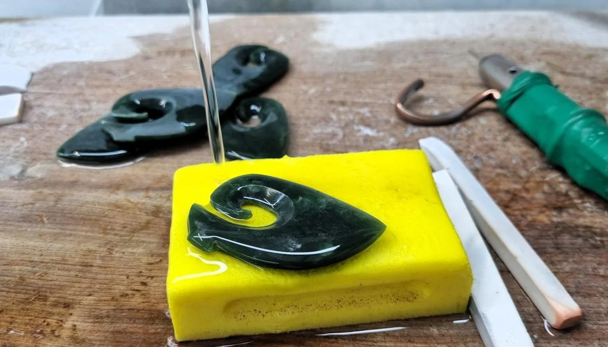 A cleaned pounamu pendant on a sponge with water running over it.