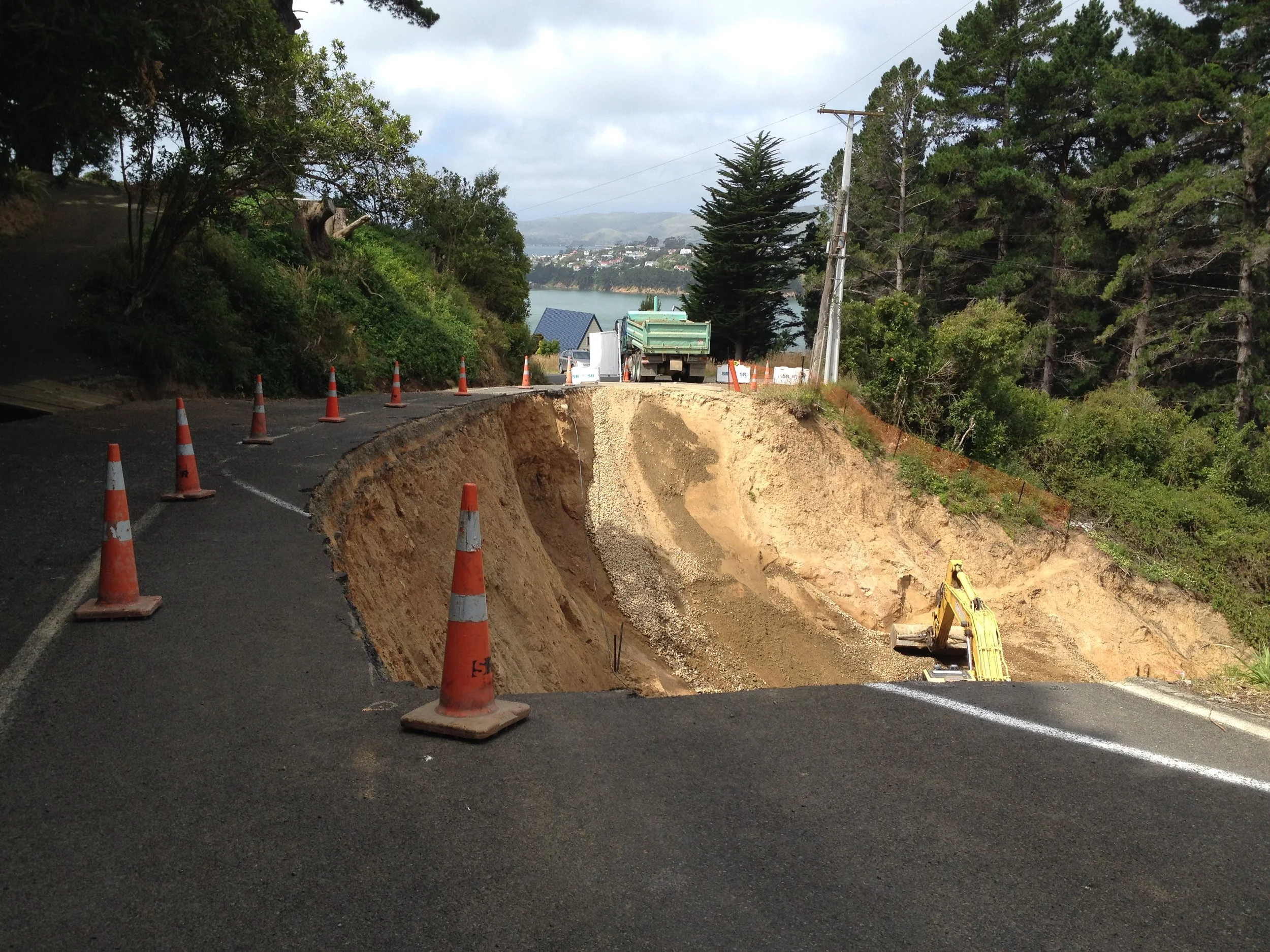 A landslide that has taken out most of a road in an urban area.