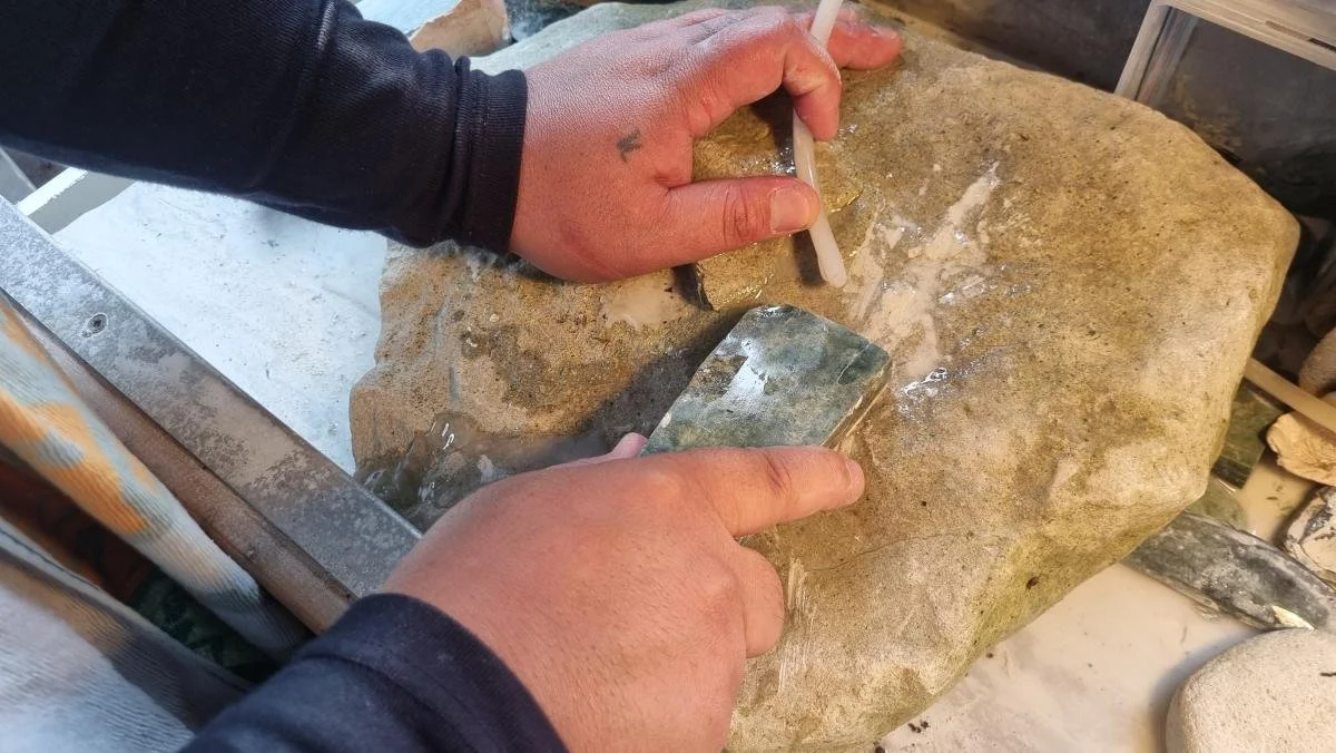 A piece of pounamu being honed on a rock.