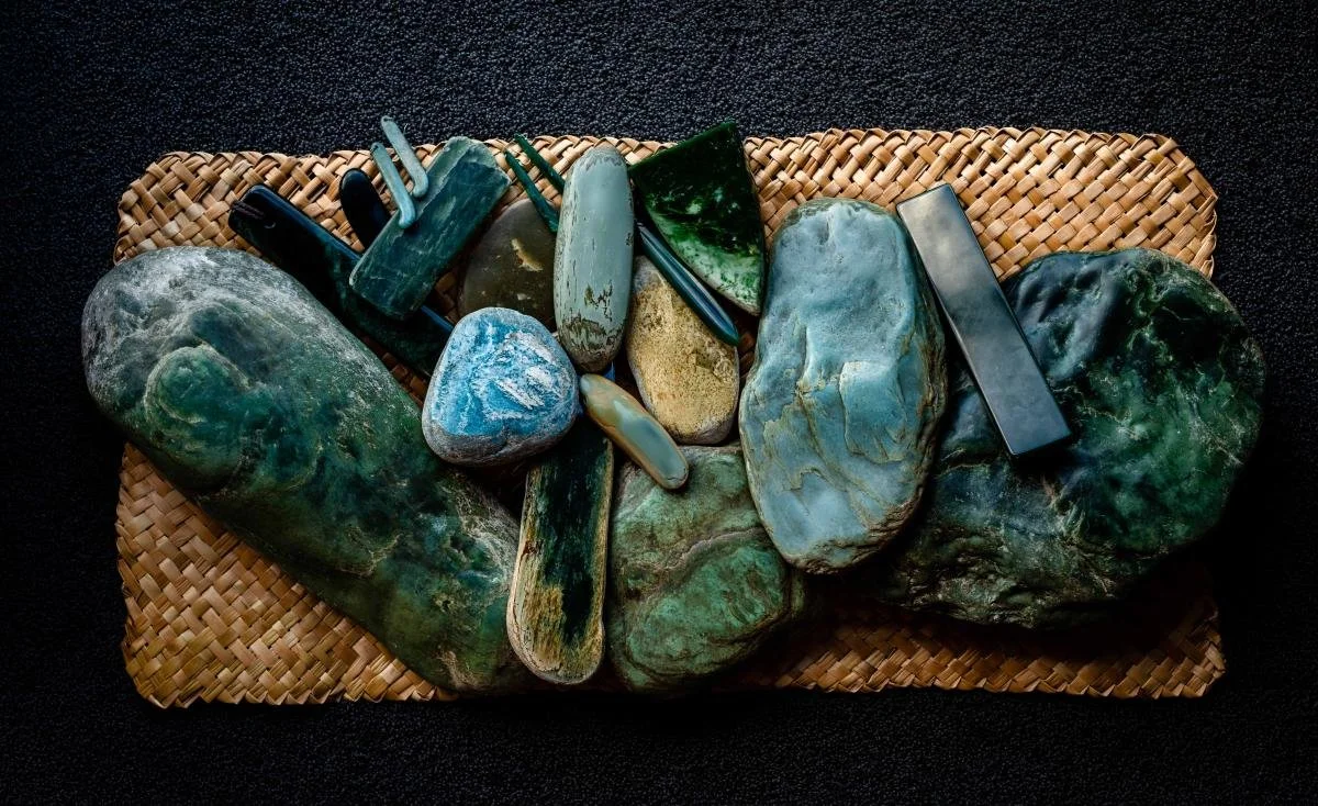 A variety of pounamu stones and pendants on a flax kete.