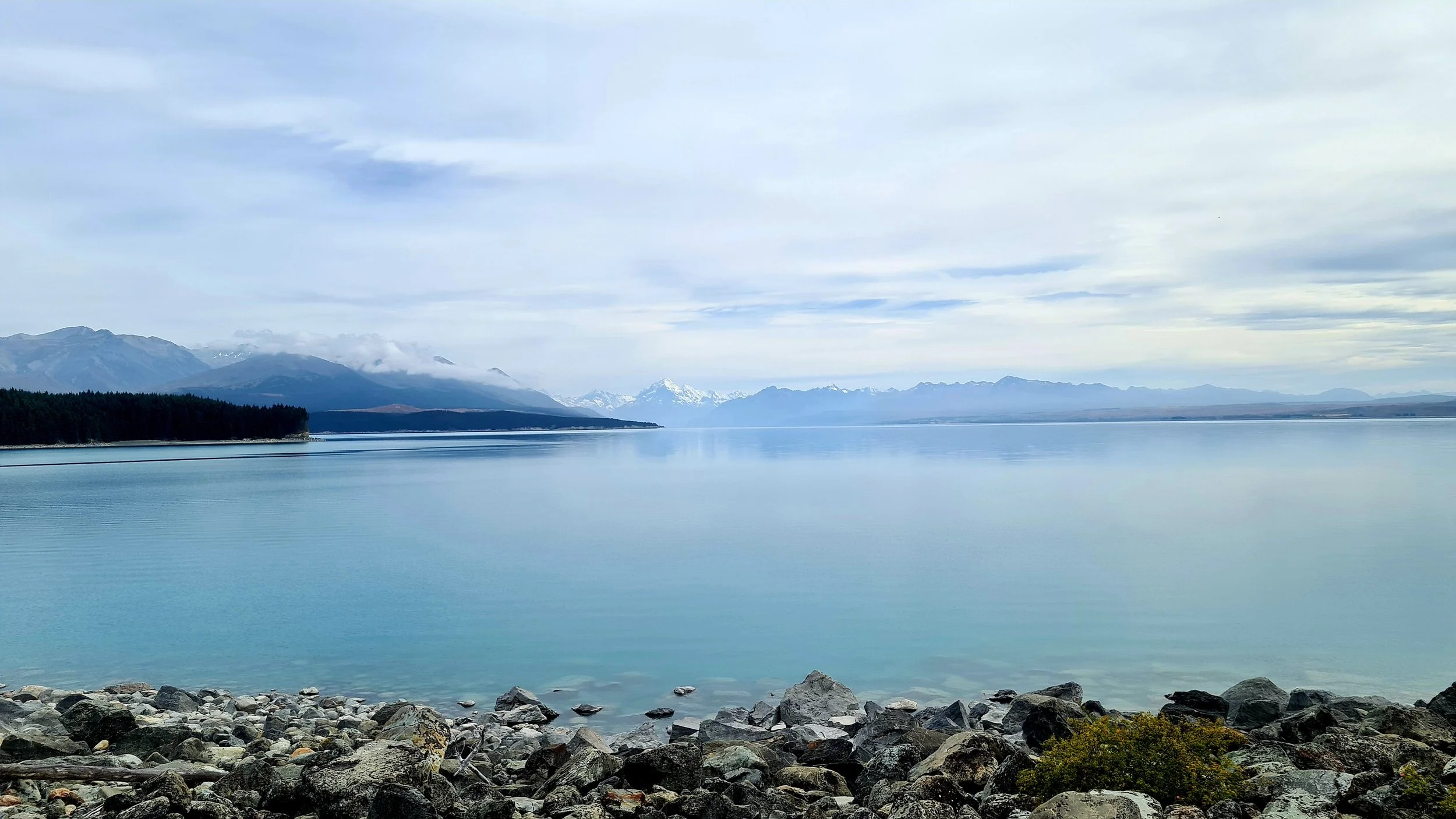 An image of Lake Pūkaki with mountain ranges in the background.