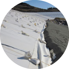 Snow-covered ground with some rocks and a clear sky. A frozen body of water or ice surface is visible in the distance.