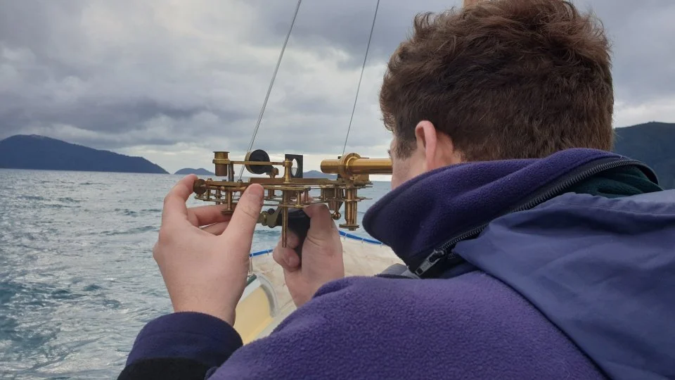 A person aboard a ship using a sextant.