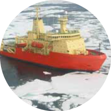 A large icebreaker ship with a red hull and yellow superstructure navigating through icy waters.
