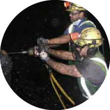 Two workers wearing safety gear handling equipment, with a dark background.