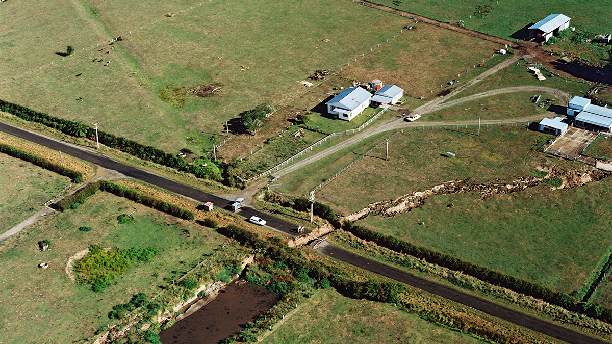 Aerial view of a large crack, caused by an earthquake, running through a farm and across the road.