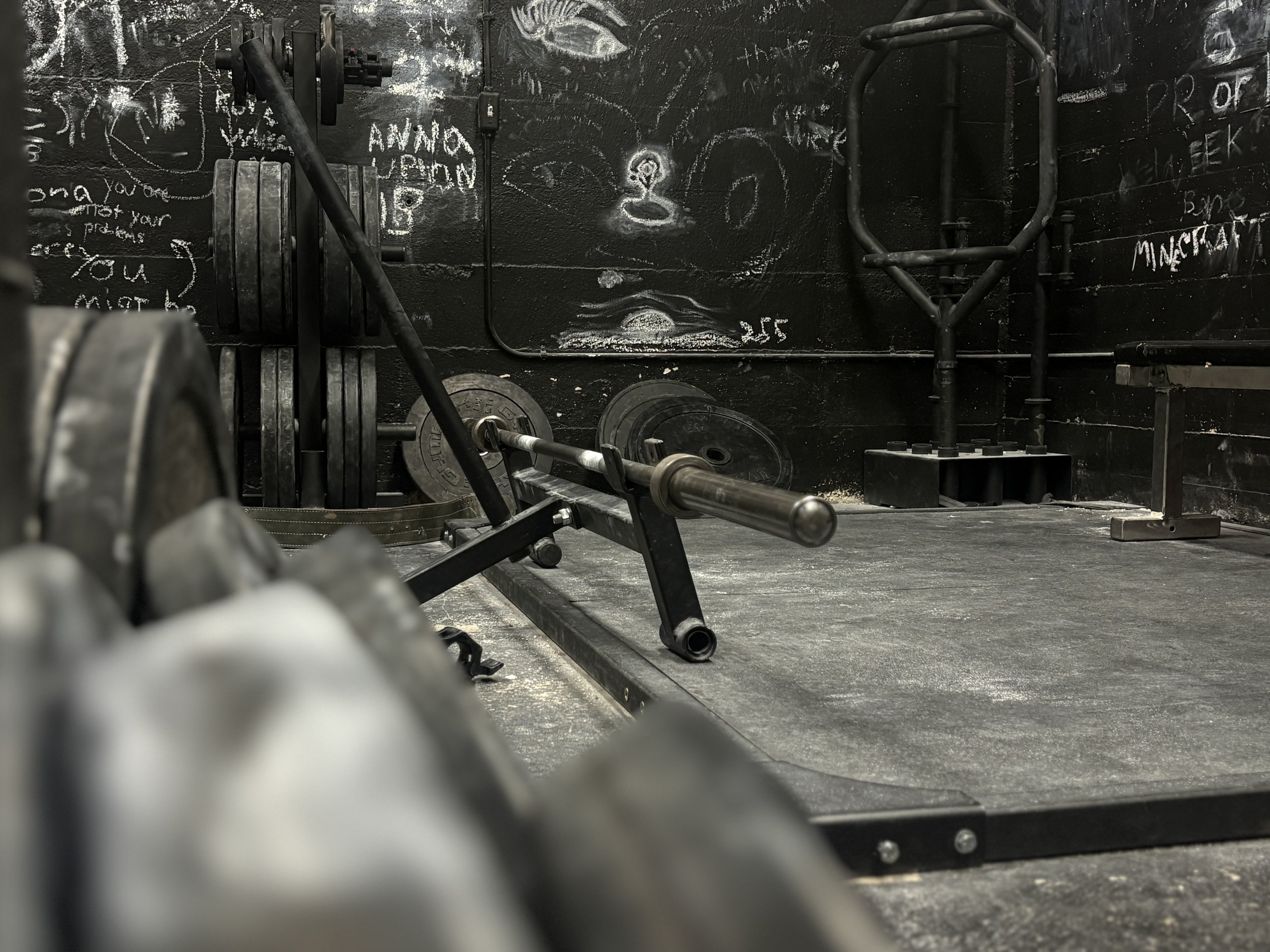 Free weights and chalk-covered training wall inside Downing’s Gym.